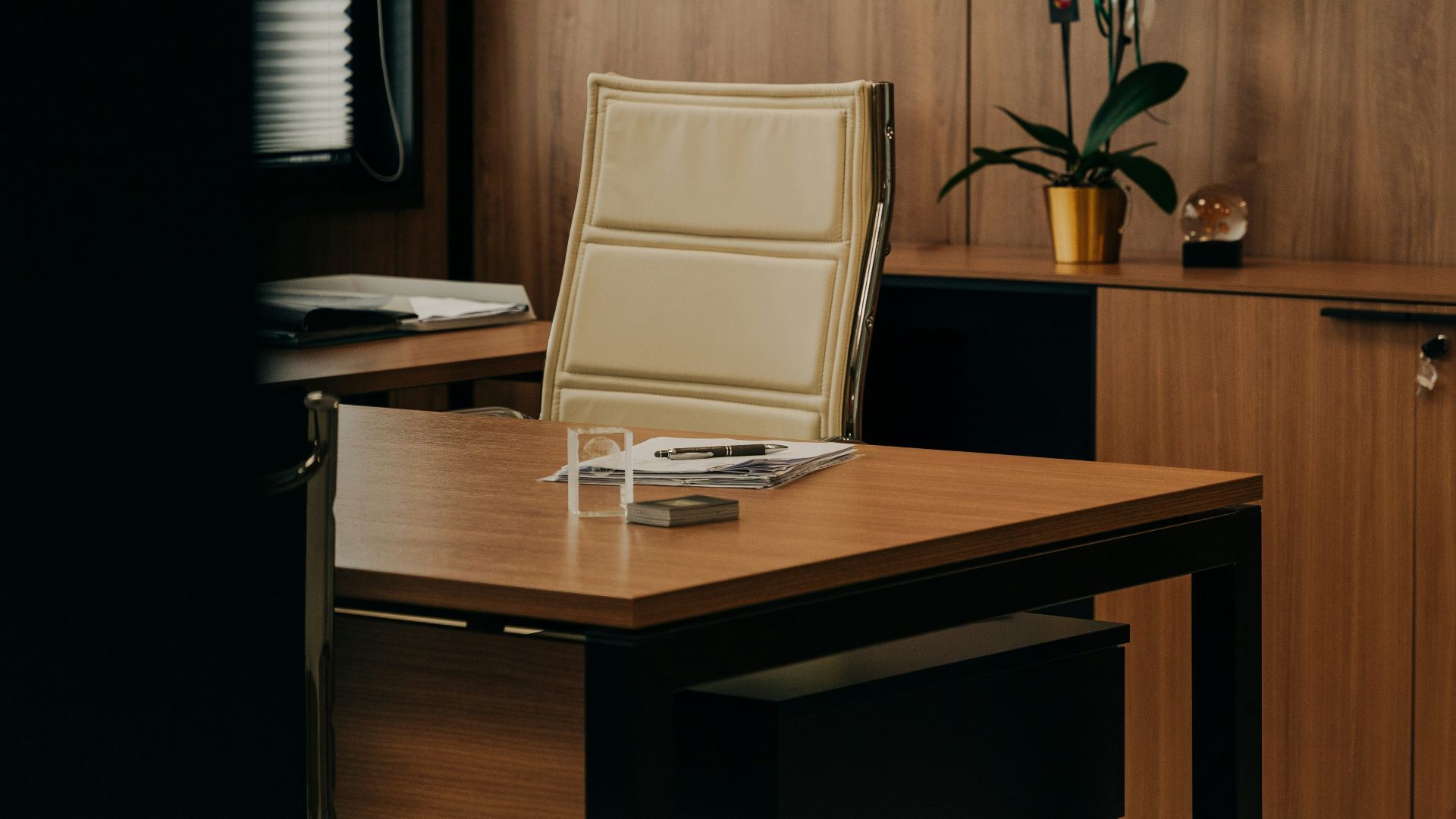 a desk with a chair and a vase of flowers