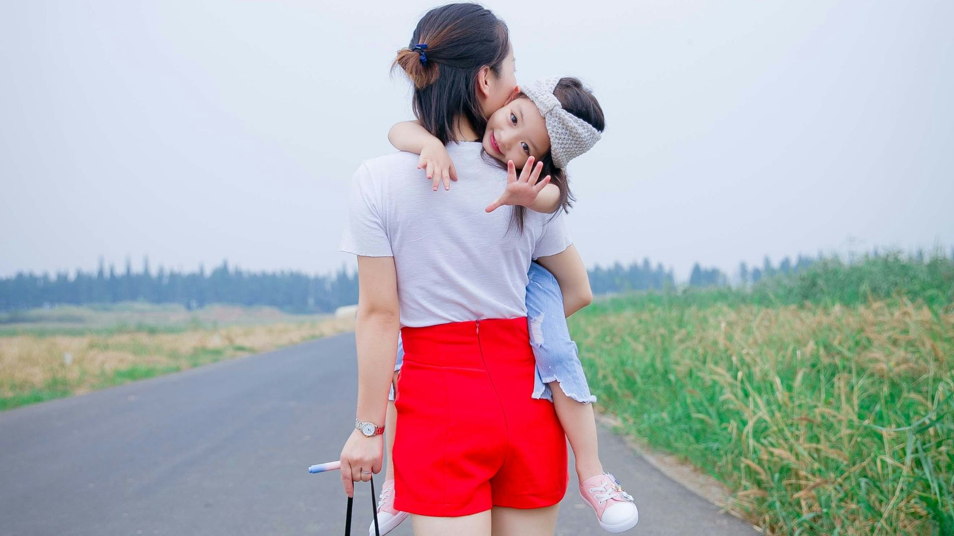 a woman holding a child on her back on a road