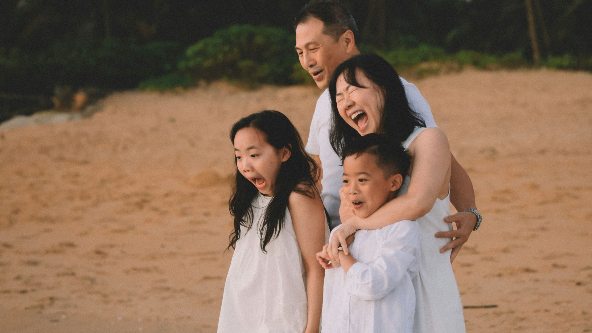 A family poses on a beach at sunset.