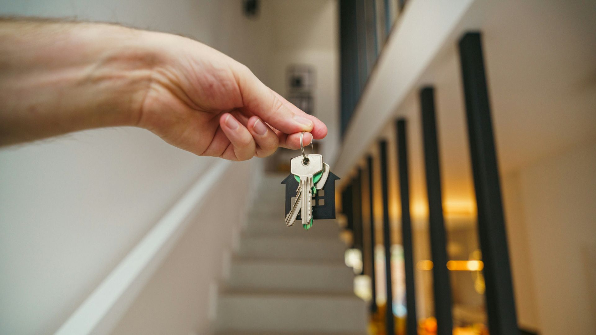 Here's a possible caption: keys being held in front of a staircase.