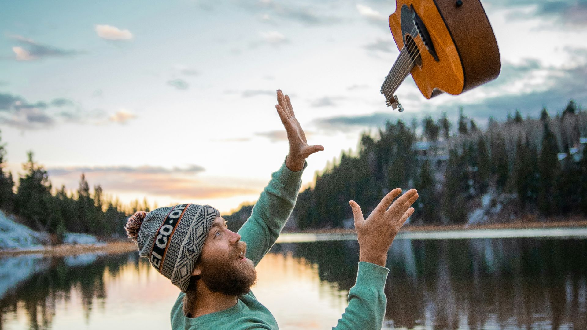 man in green jacket and brown hat standing near lake during daytime