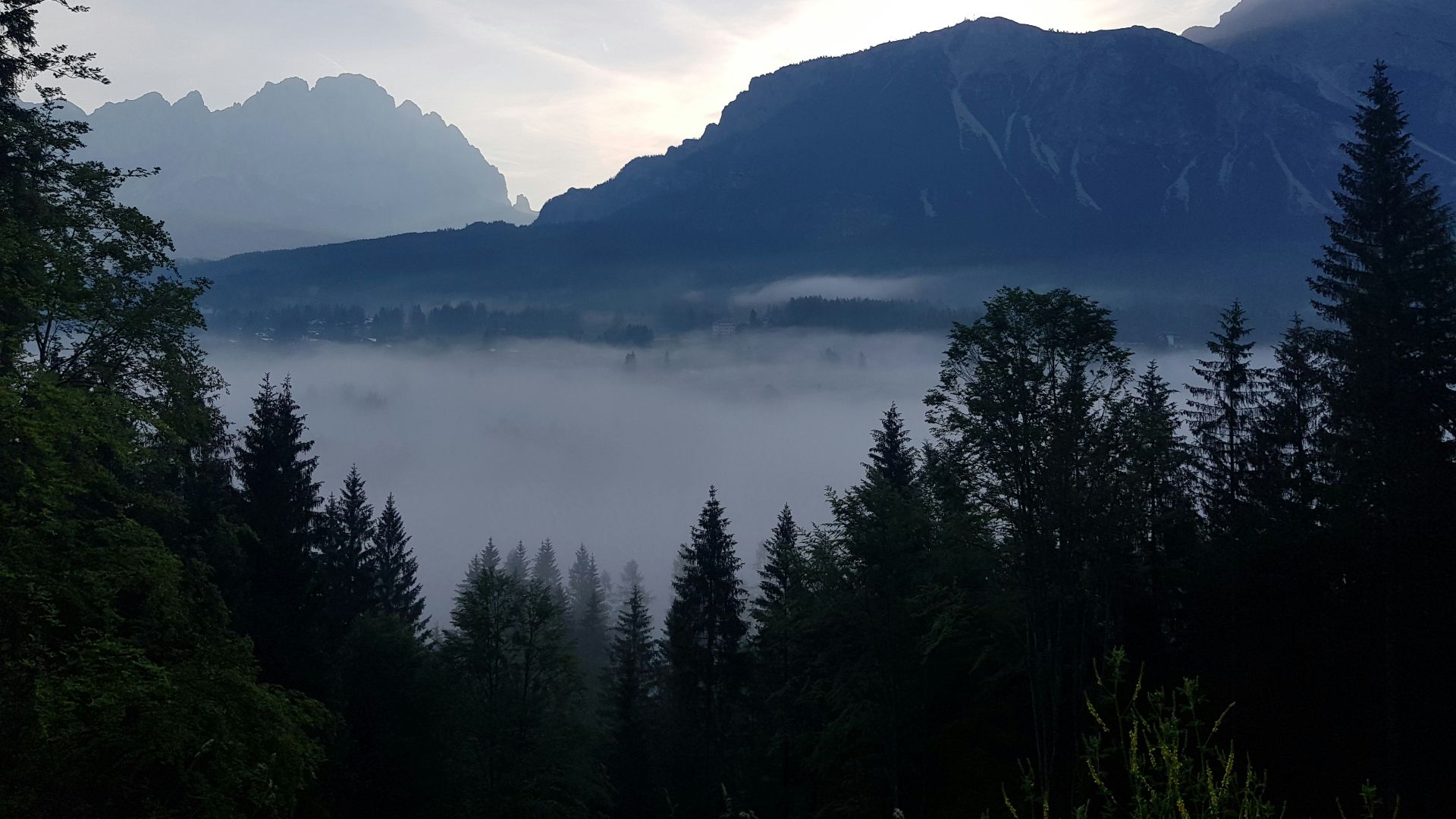 a view of a mountain range with trees in the foreground