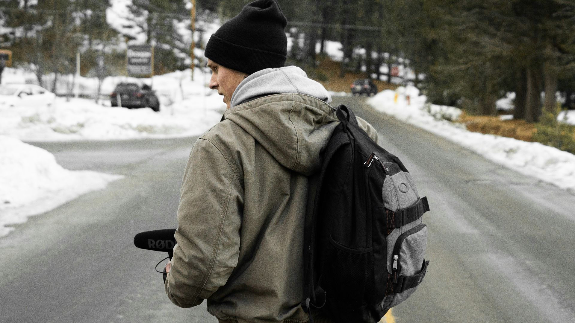 man wearing gray jacket and black backpack