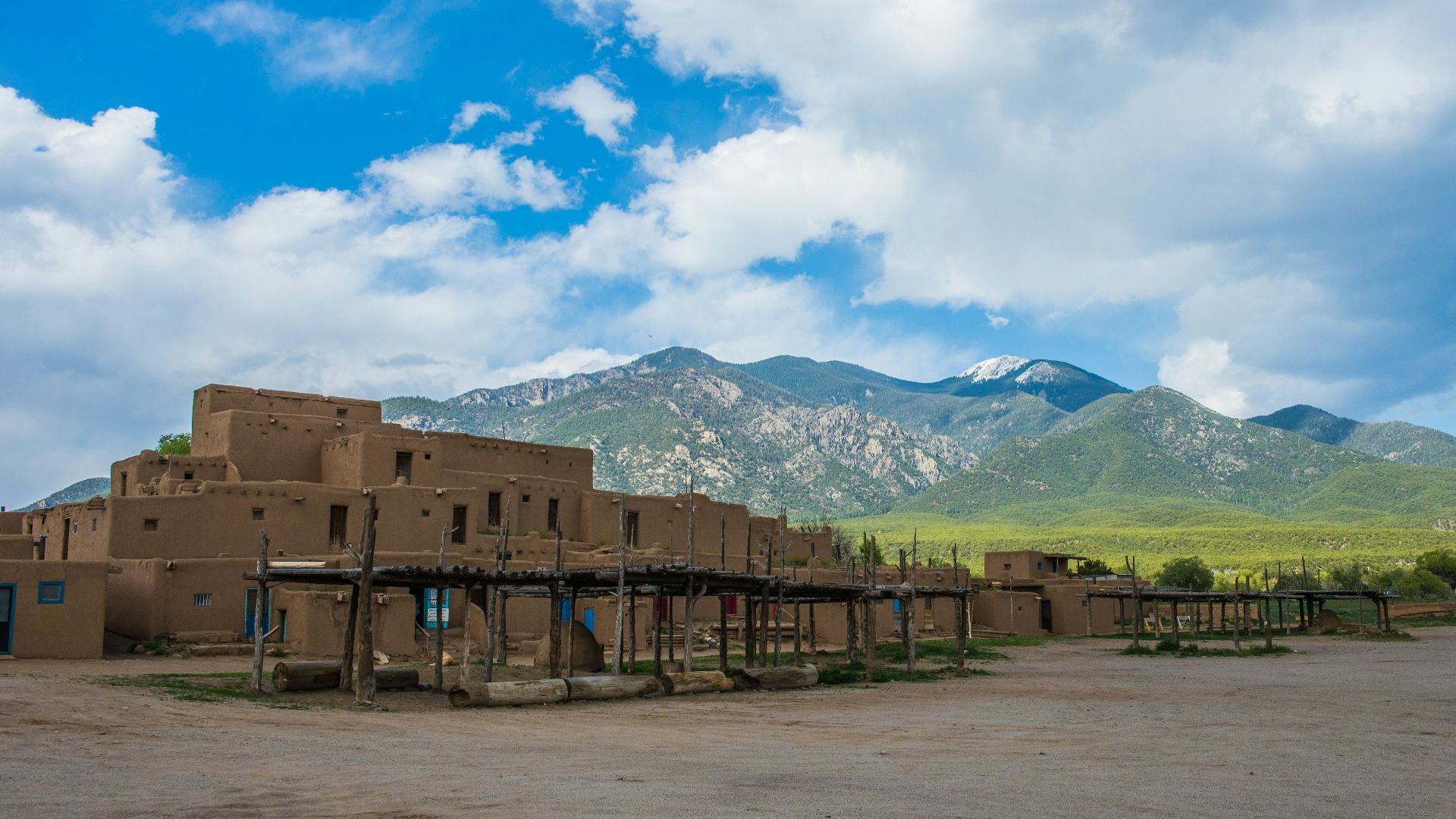 a large adobe building with mountains in the background