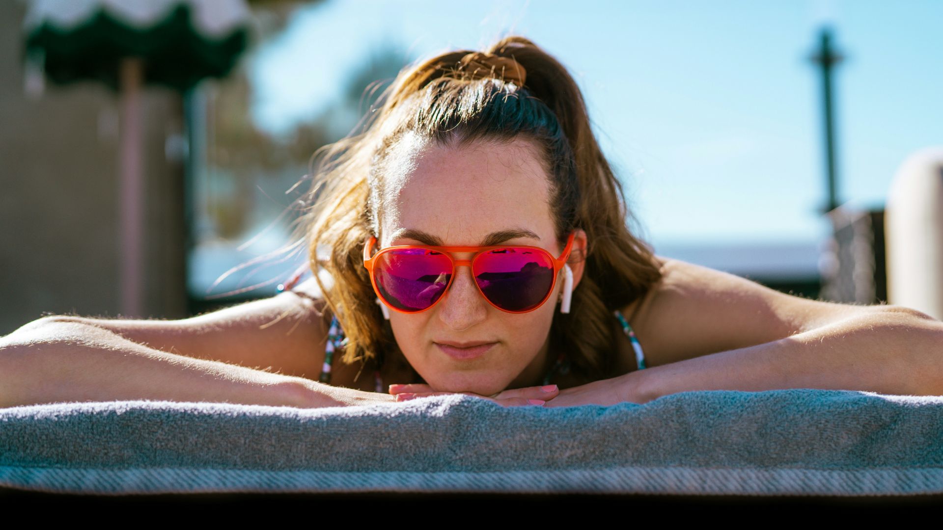 a woman wearing sunglasses laying on a towel