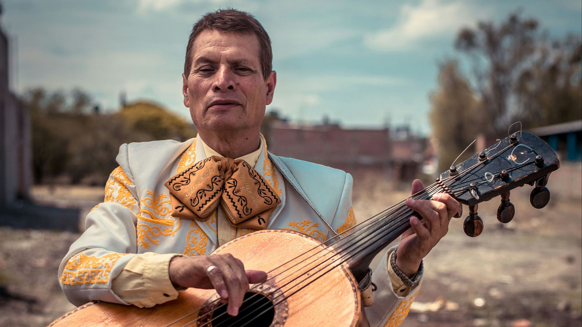 standing man holding brown sting musical guitar during daytime