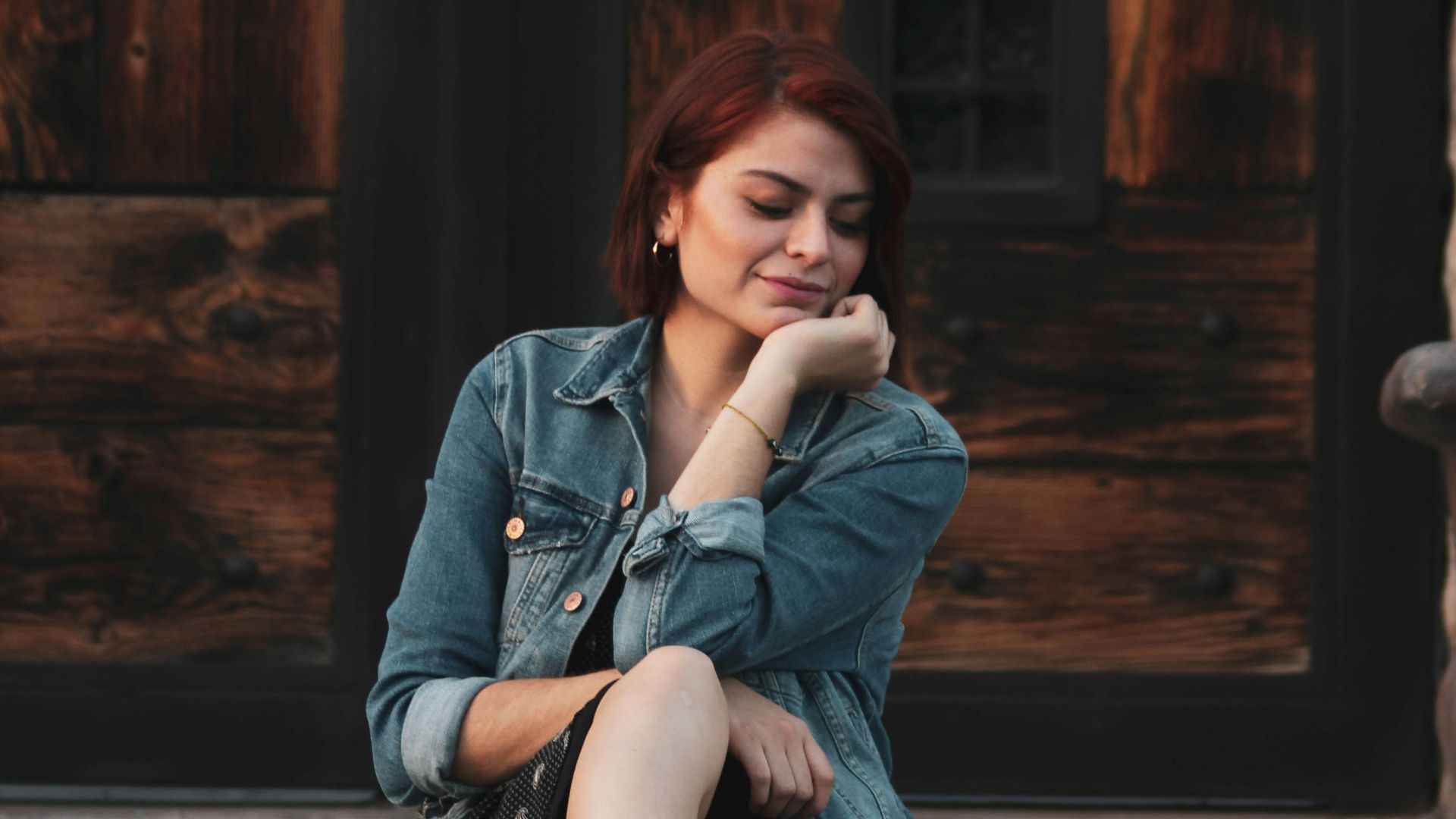 woman wearing blue denim jacet sitting on pavement