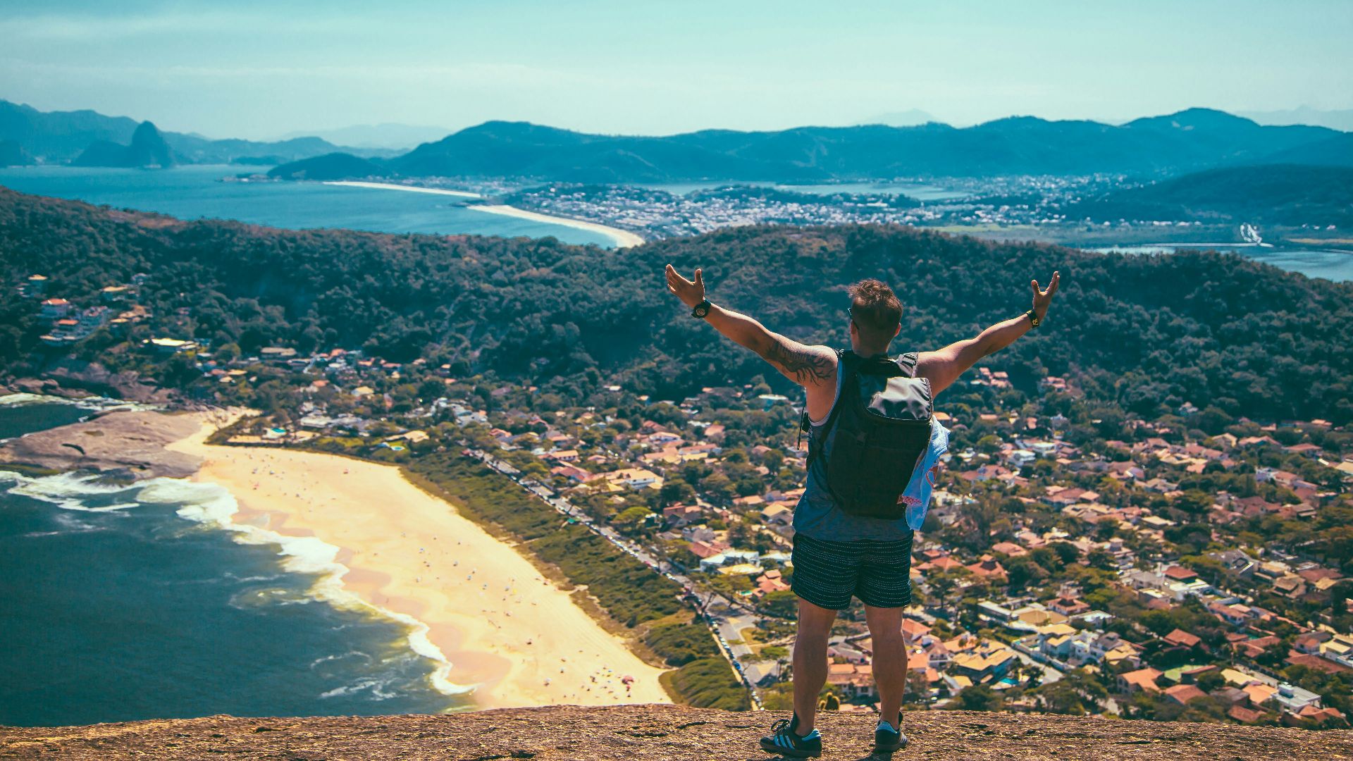 man standing front of seashore and houses