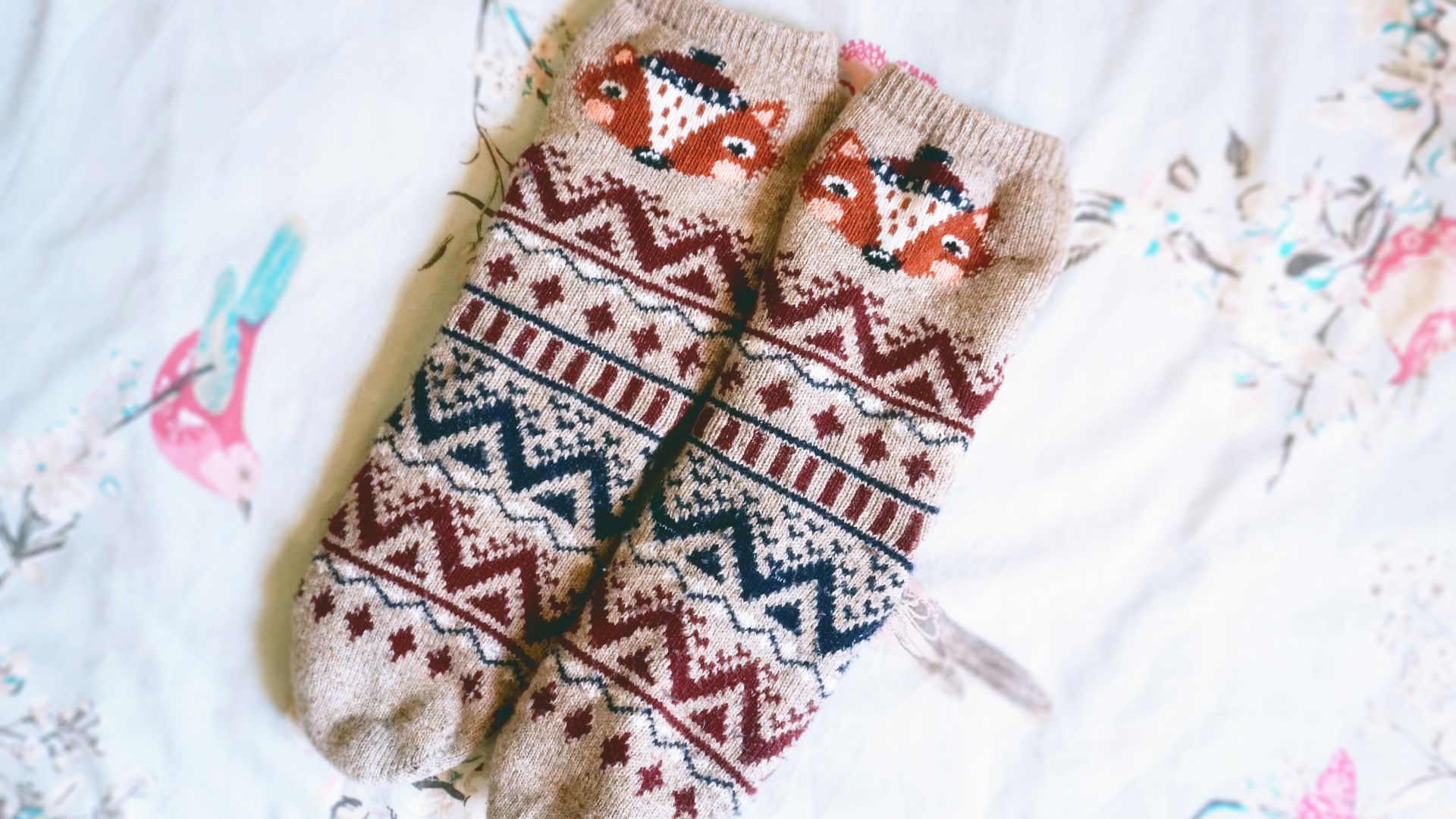 A pair of mittens sitting on top of a bed