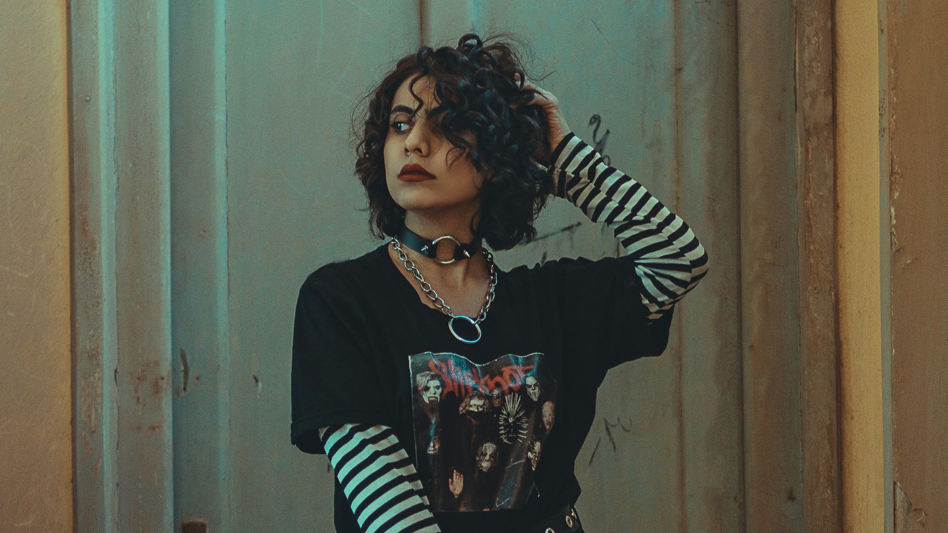 woman in black and white long sleeve shirt and black pants standing beside brown wooden door