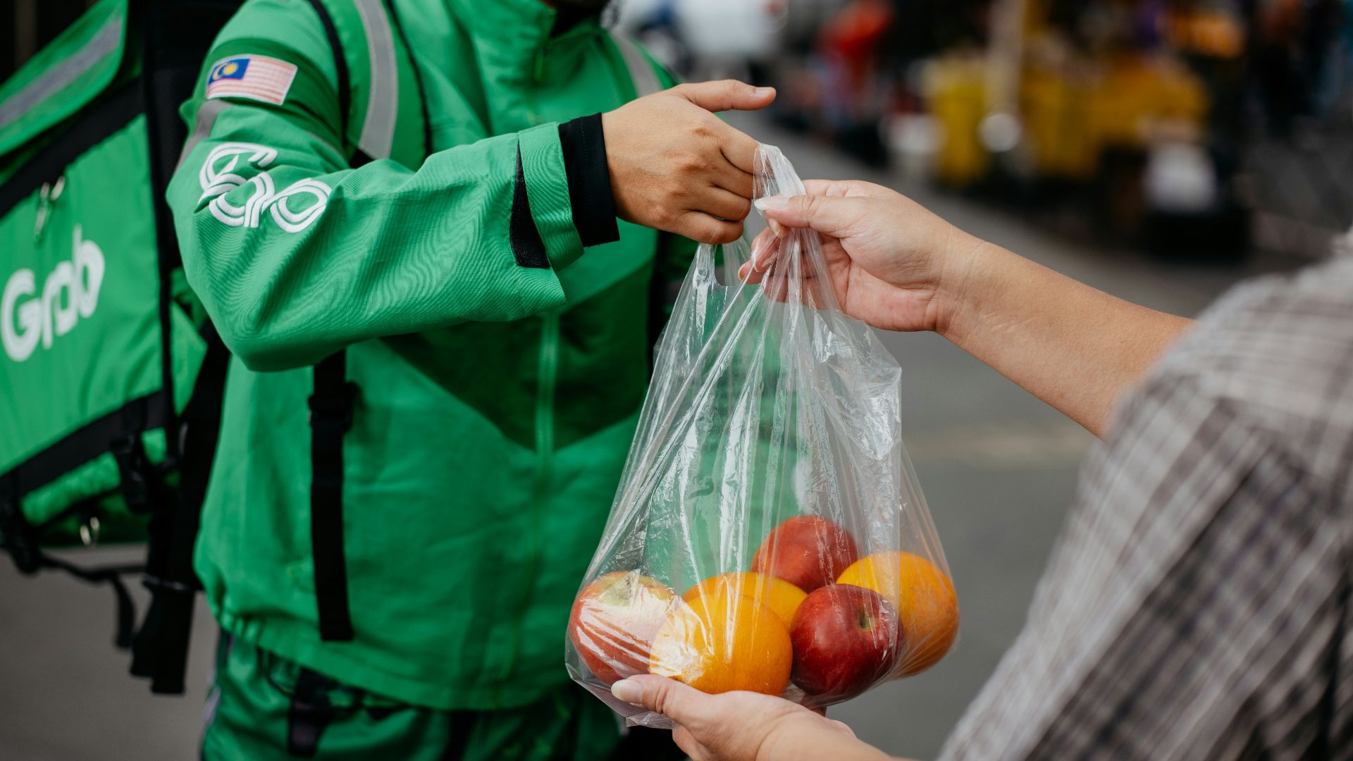 a man handing a bag of fruit to another man