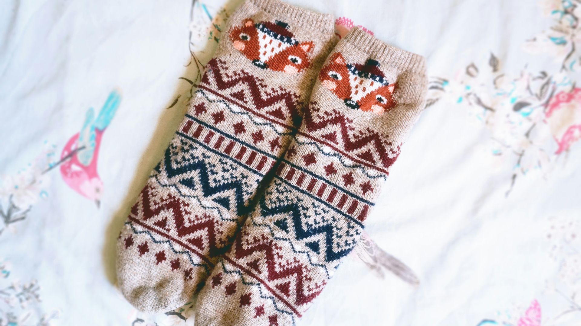 A pair of mittens sitting on top of a bed