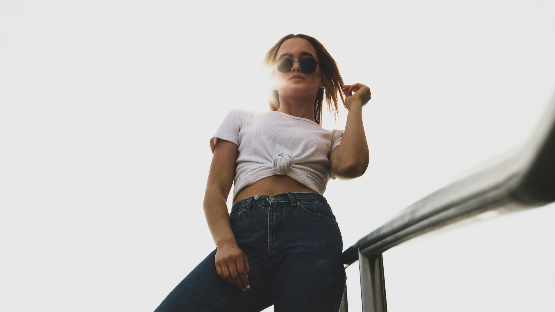 woman wearing white crop top and black pants standing near gray handrails during daytime