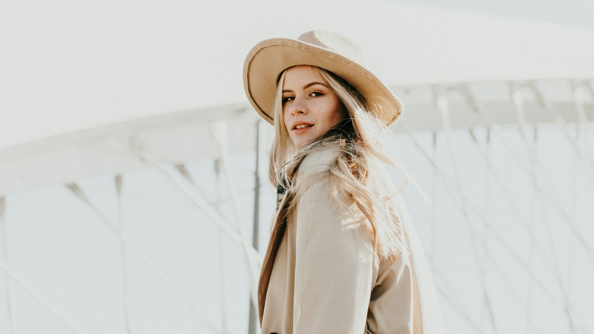 woman in brown coat wearing brown hat standing on snow covered ground during daytime