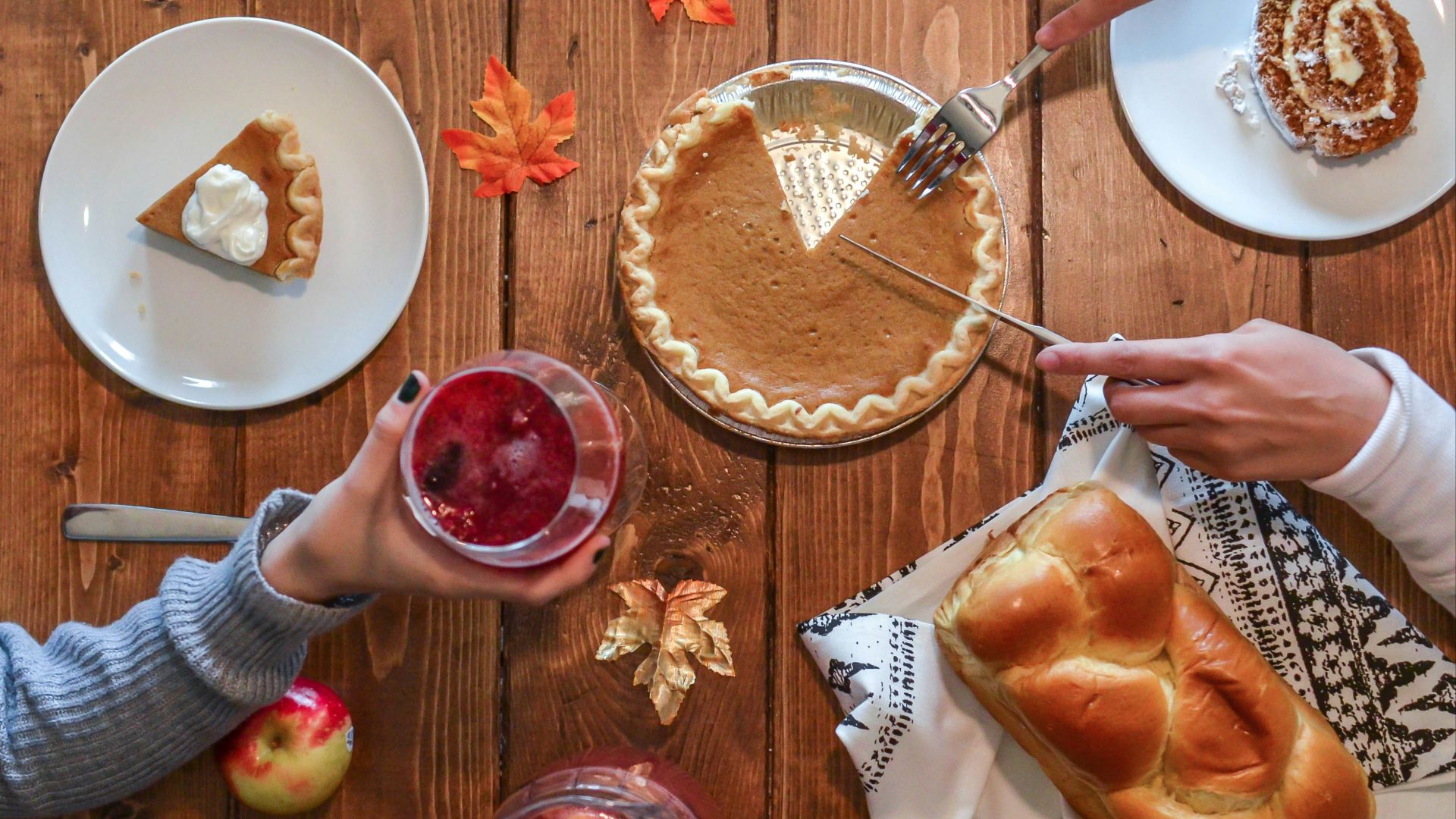 person slicing pie beside bread