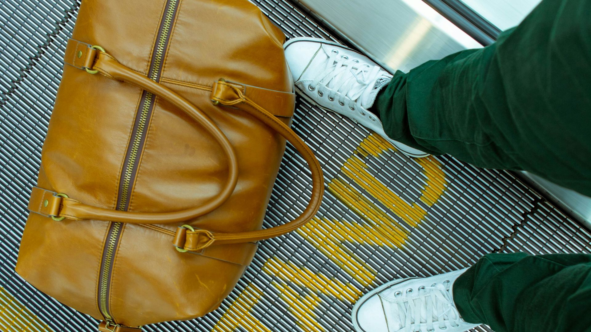 person stranding beside brown leather handbag