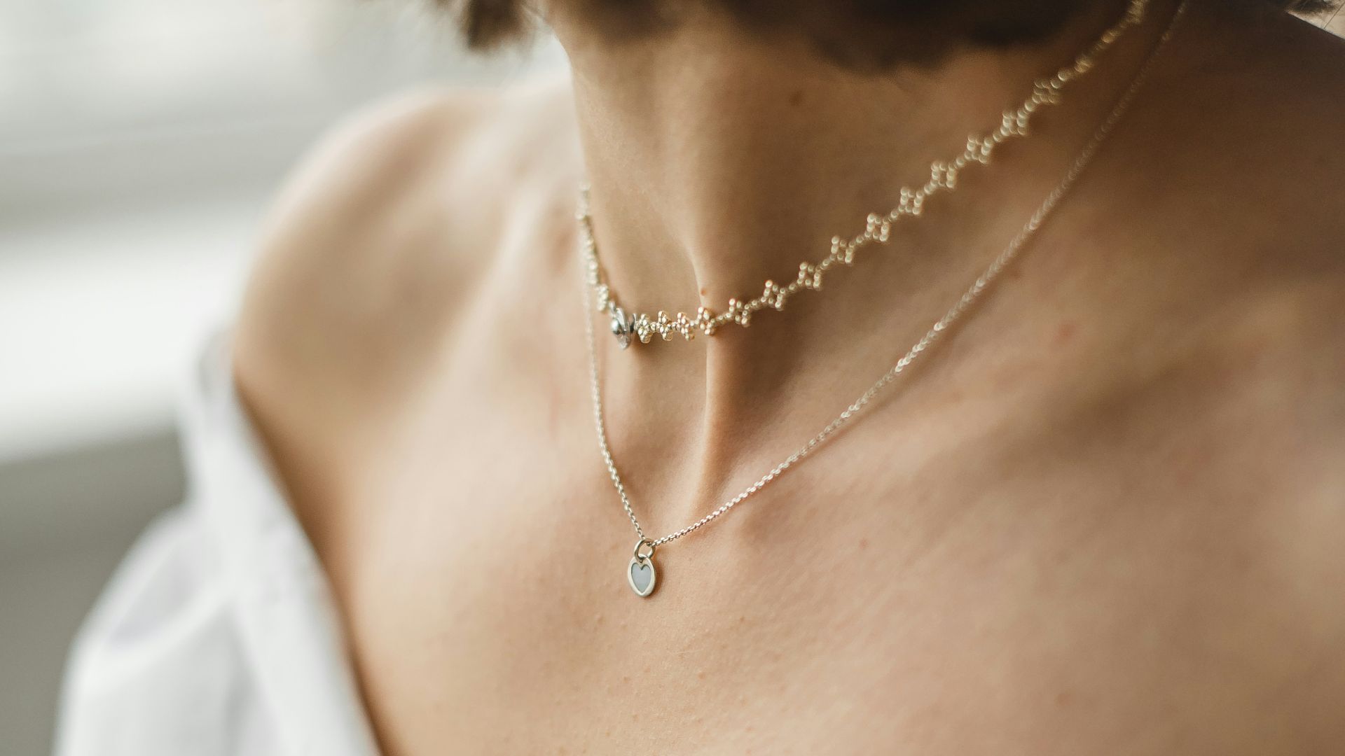 woman in white off shoulder shirt wearing silver necklace