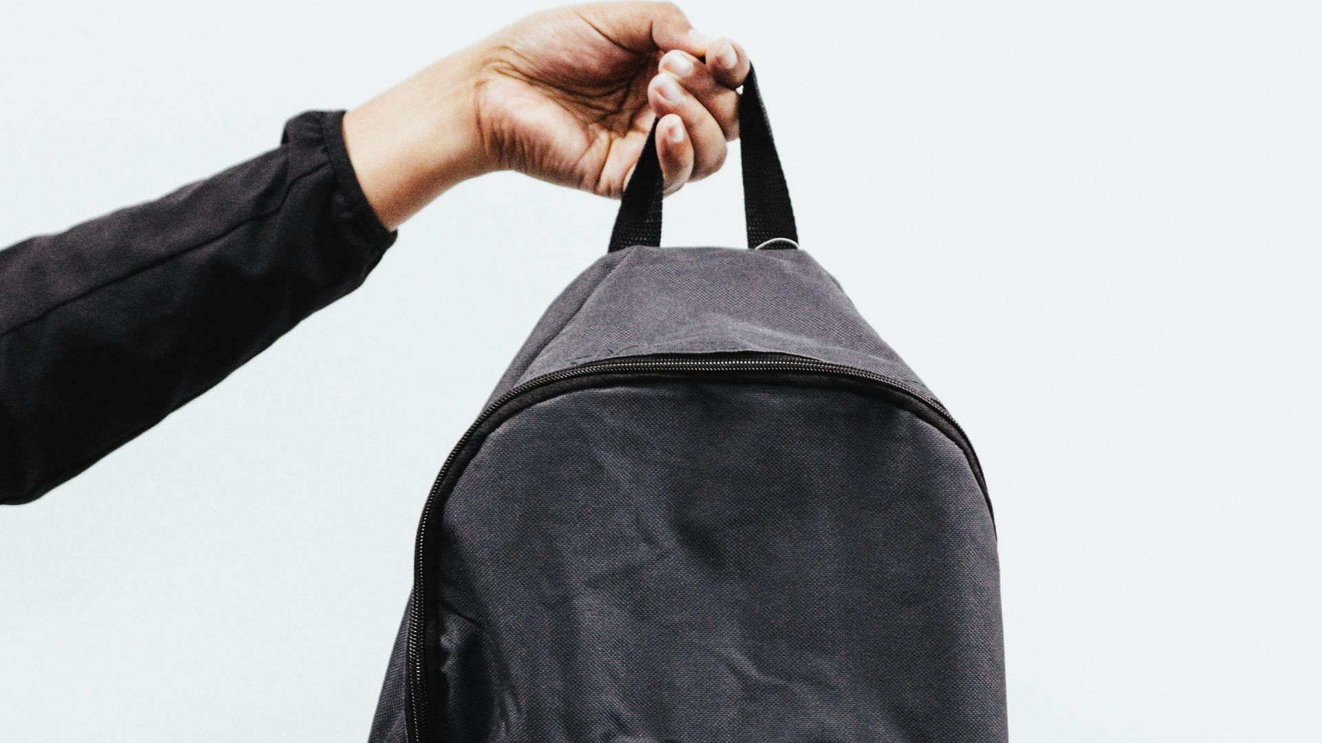 person in black jacket holding black backpack