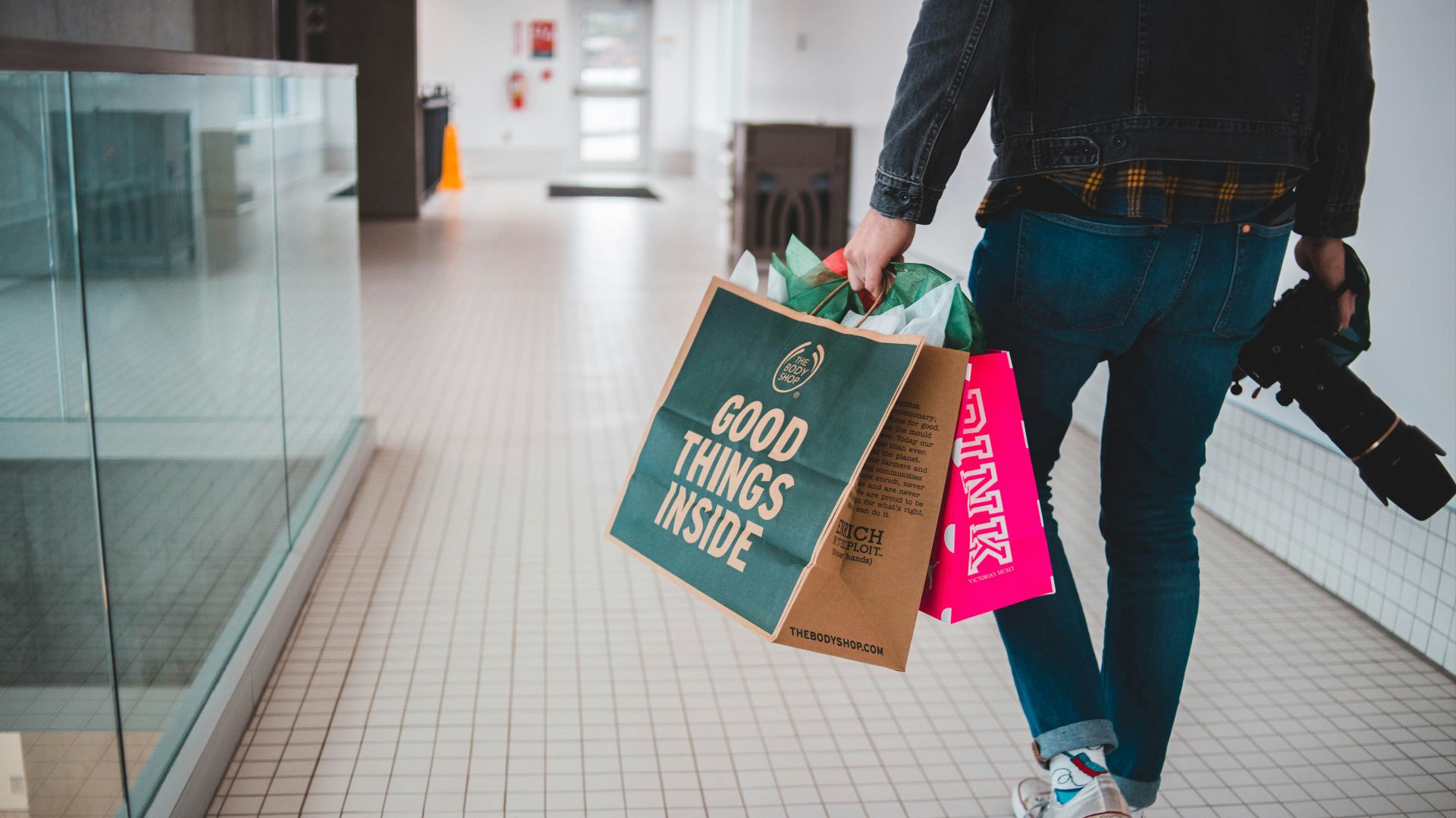 person walking while carrying a camera and paper bags