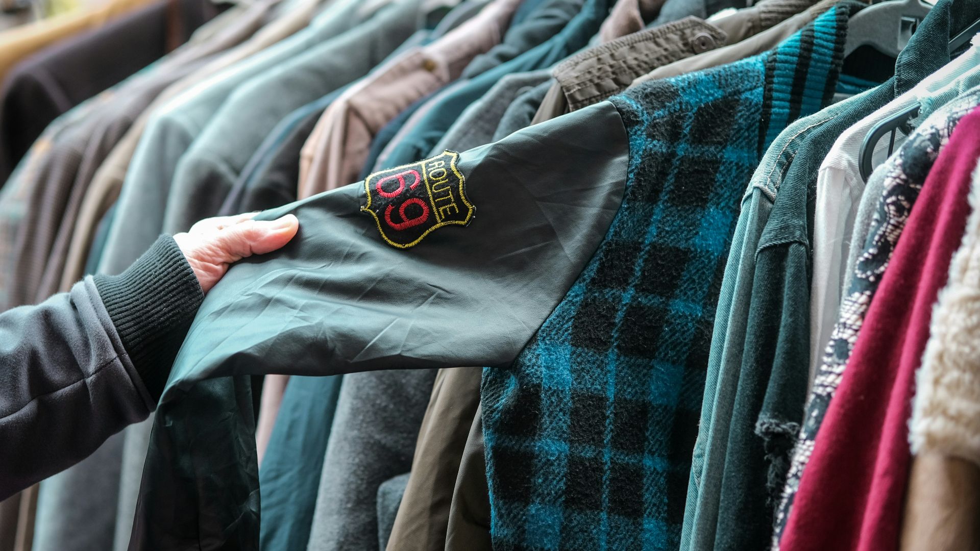a person holding a shirt in front of a rack of shirts