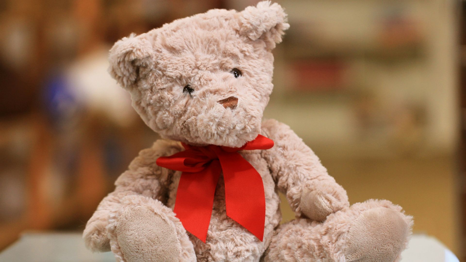 selective focus photo of brown teddy bear with red bow