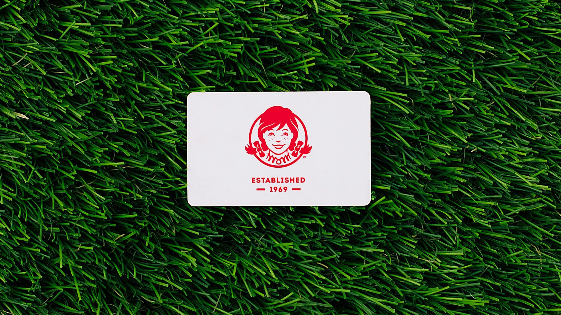 a white square sticker sitting on top of a lush green field