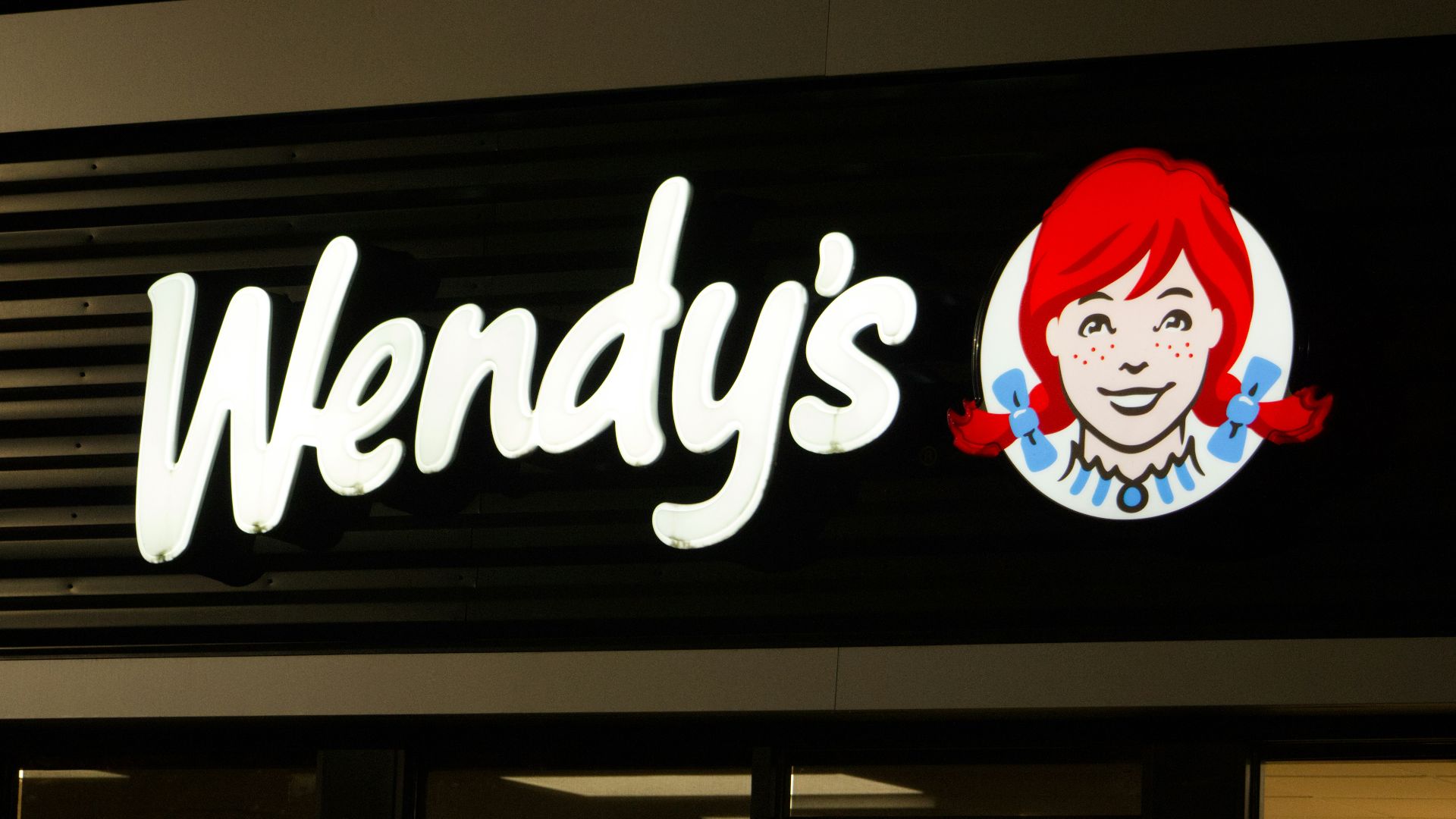 A wendy's sign is lit up at night
