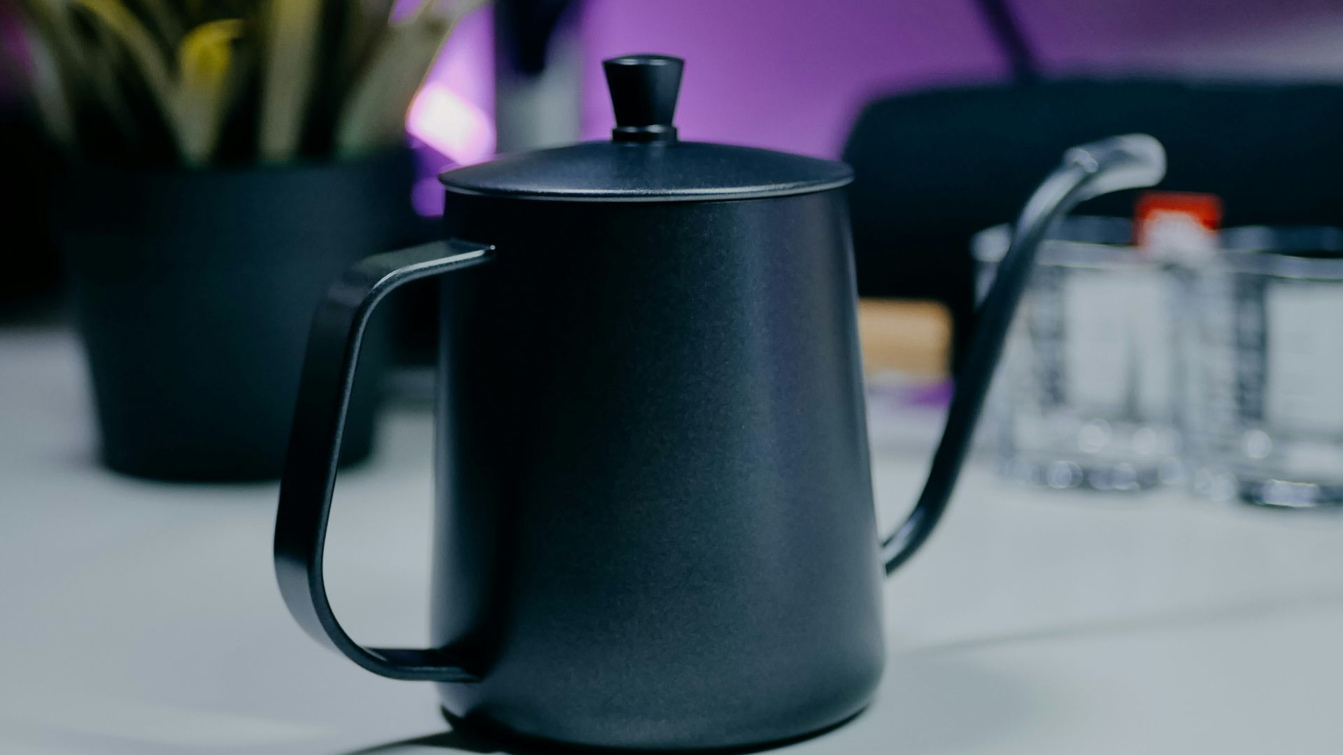 A black coffee pot sitting on top of a white table