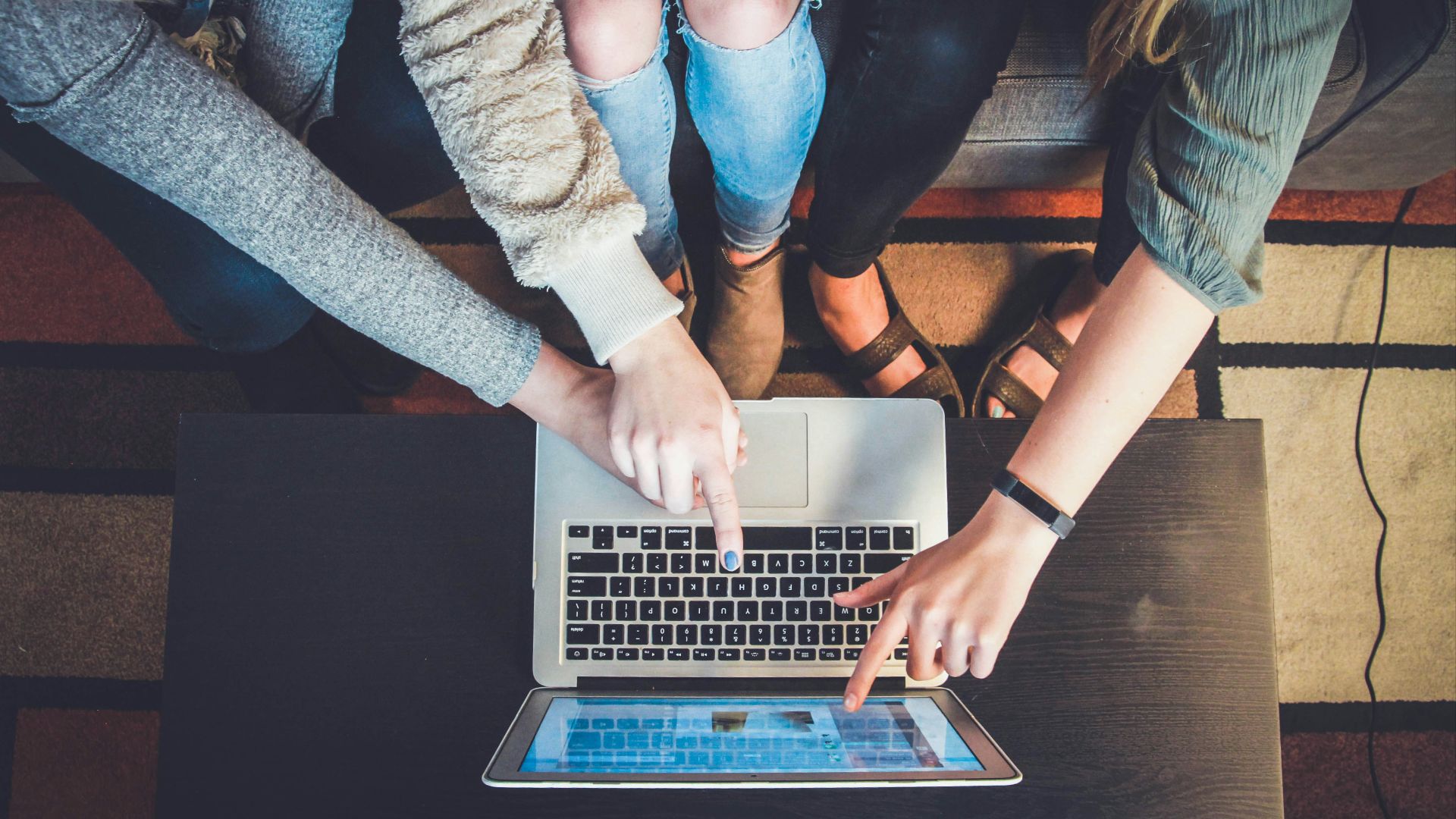 three person pointing the silver laptop computer