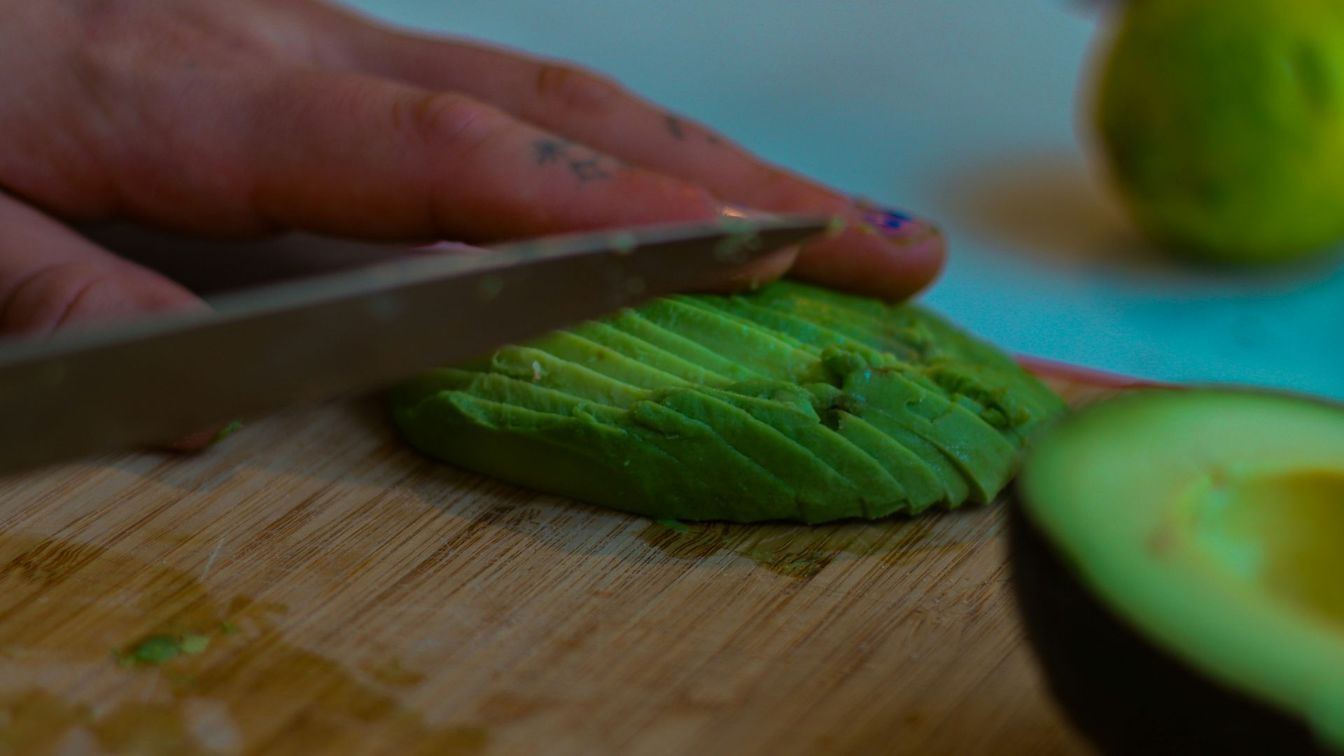 a person cutting an avocado on a cutting board