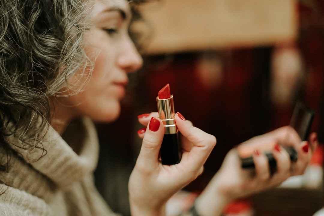 woman in gray sweater holding lipstick