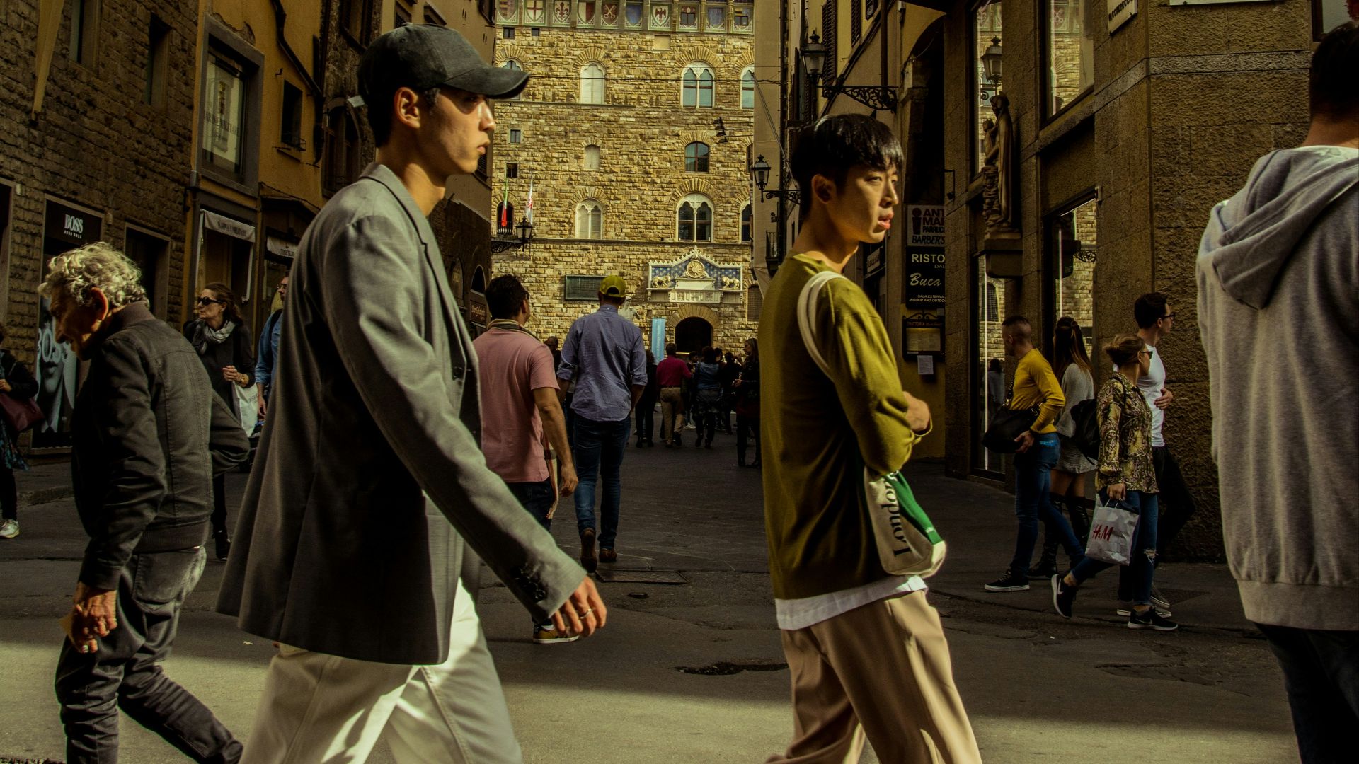 a group of people walking down a street next to tall buildings