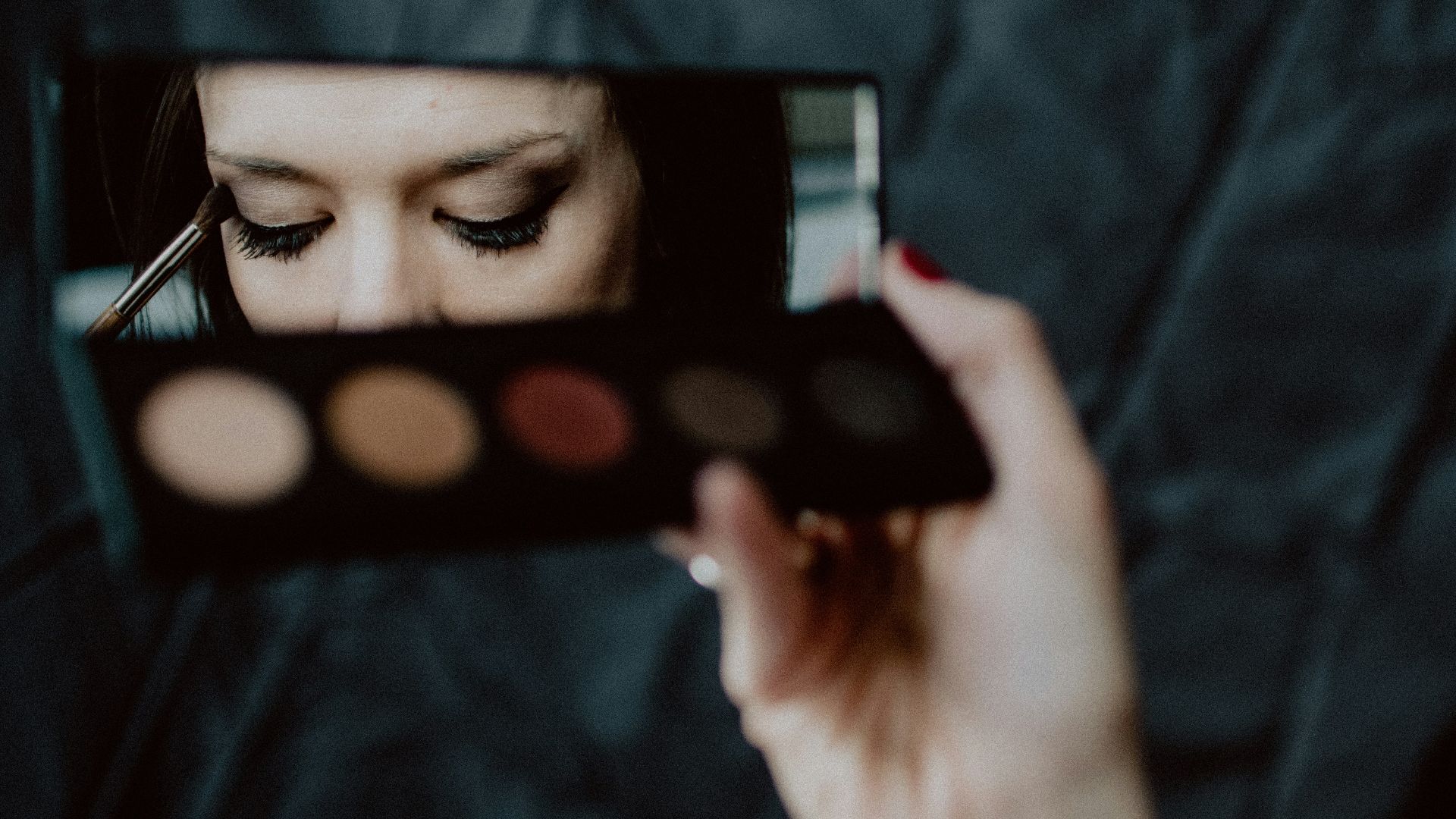 woman holding black and silver make up palette