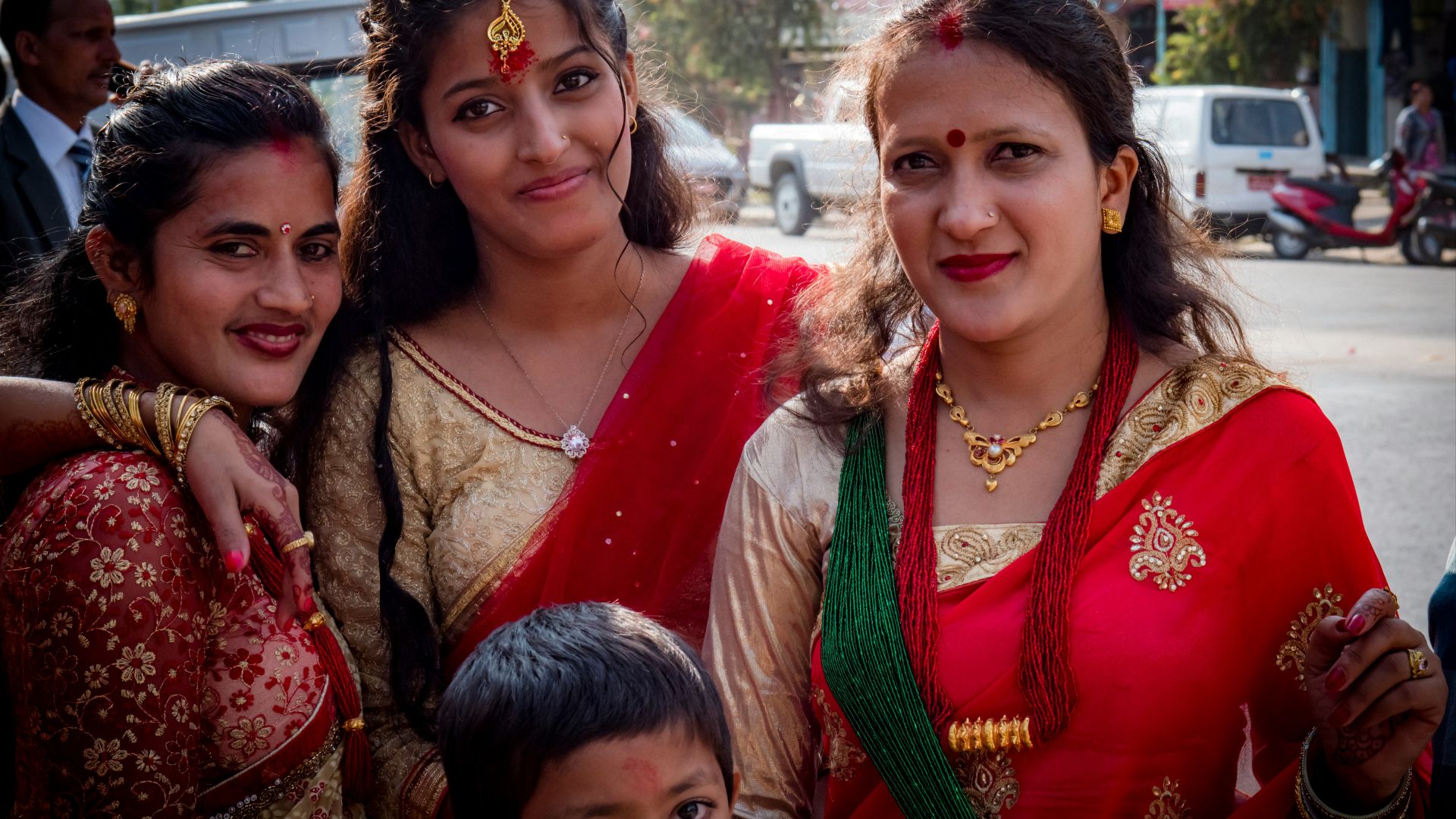 woman in red and green sari beside girl in green and brown dress