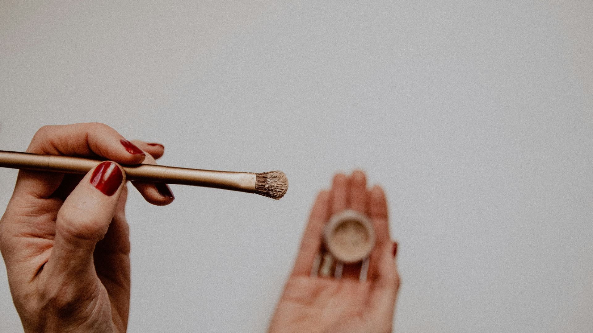 person holding brown and white makeup brush