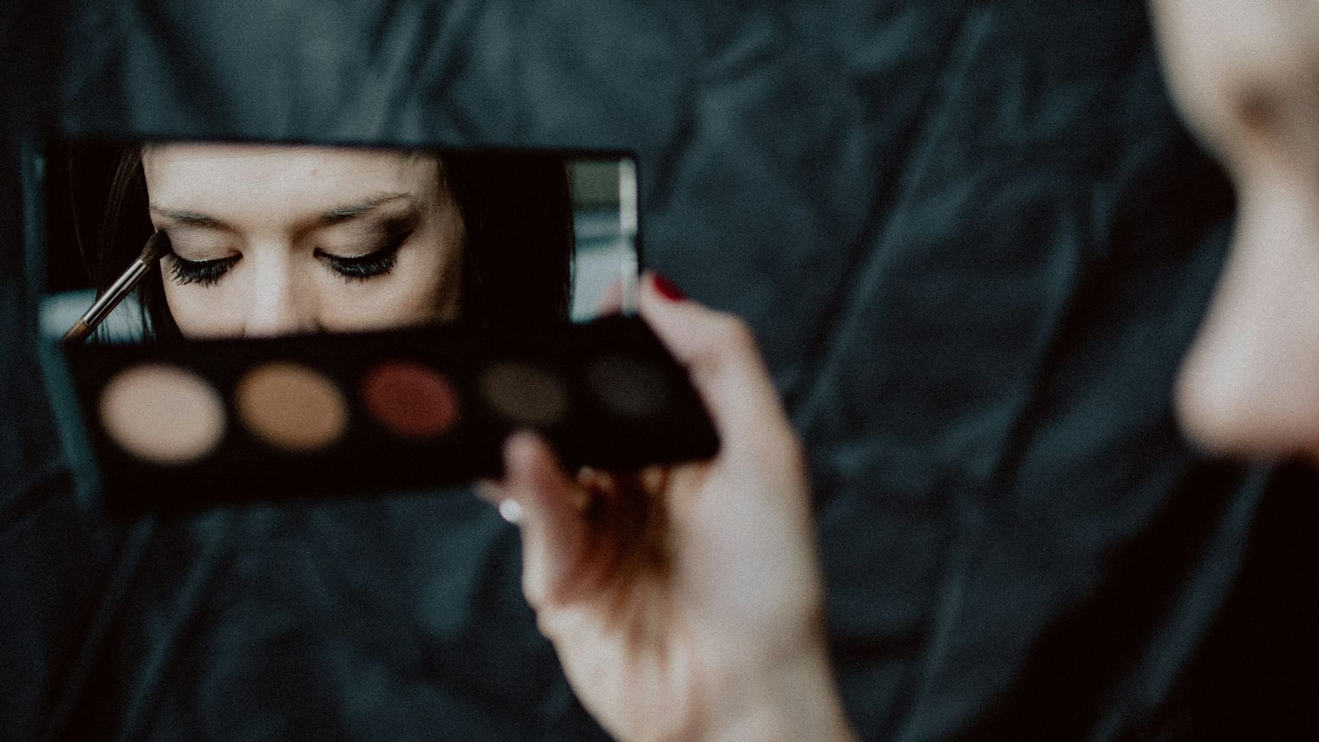 woman holding black and silver make up palette