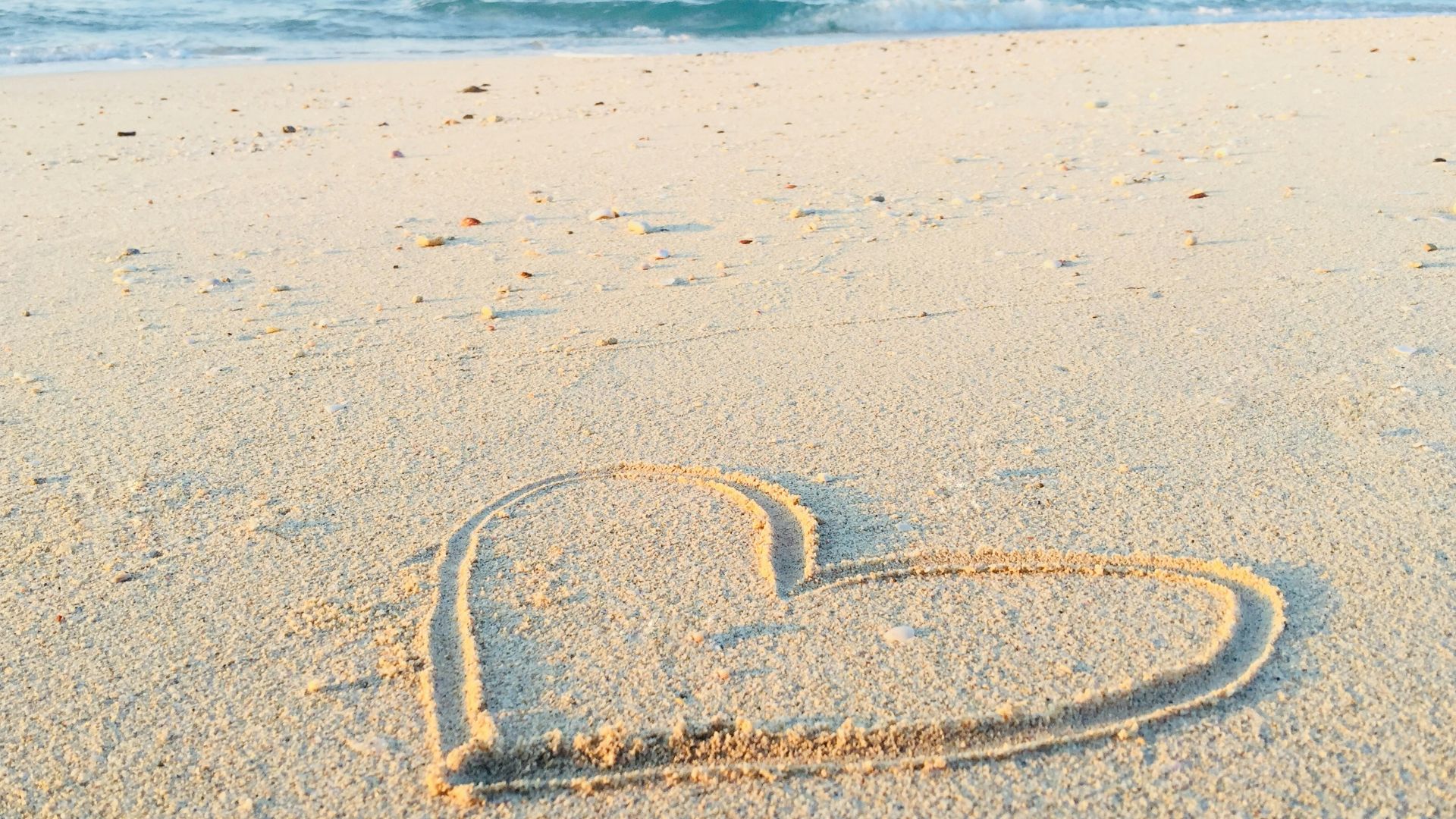 heart drawn on sand during daytime