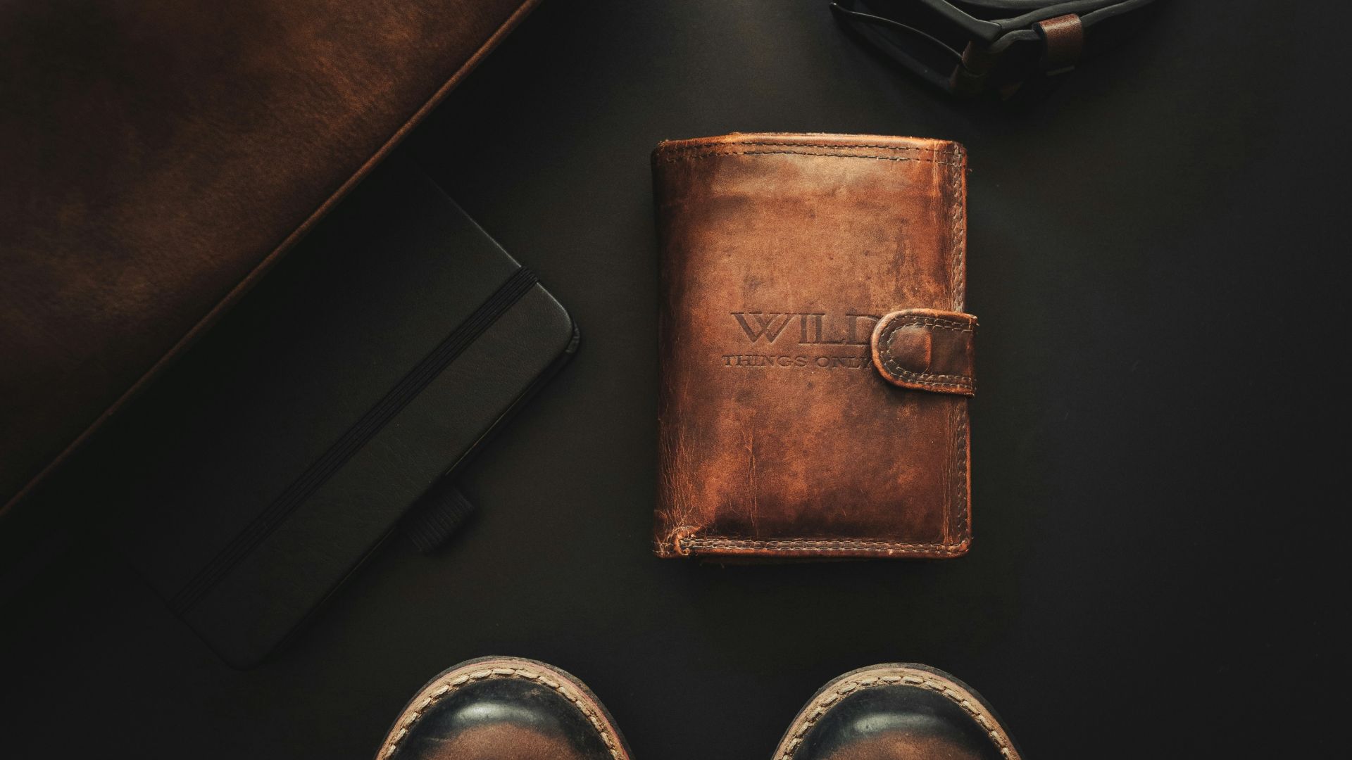 a pair of shoes, a wallet, and a belt laid out on a table