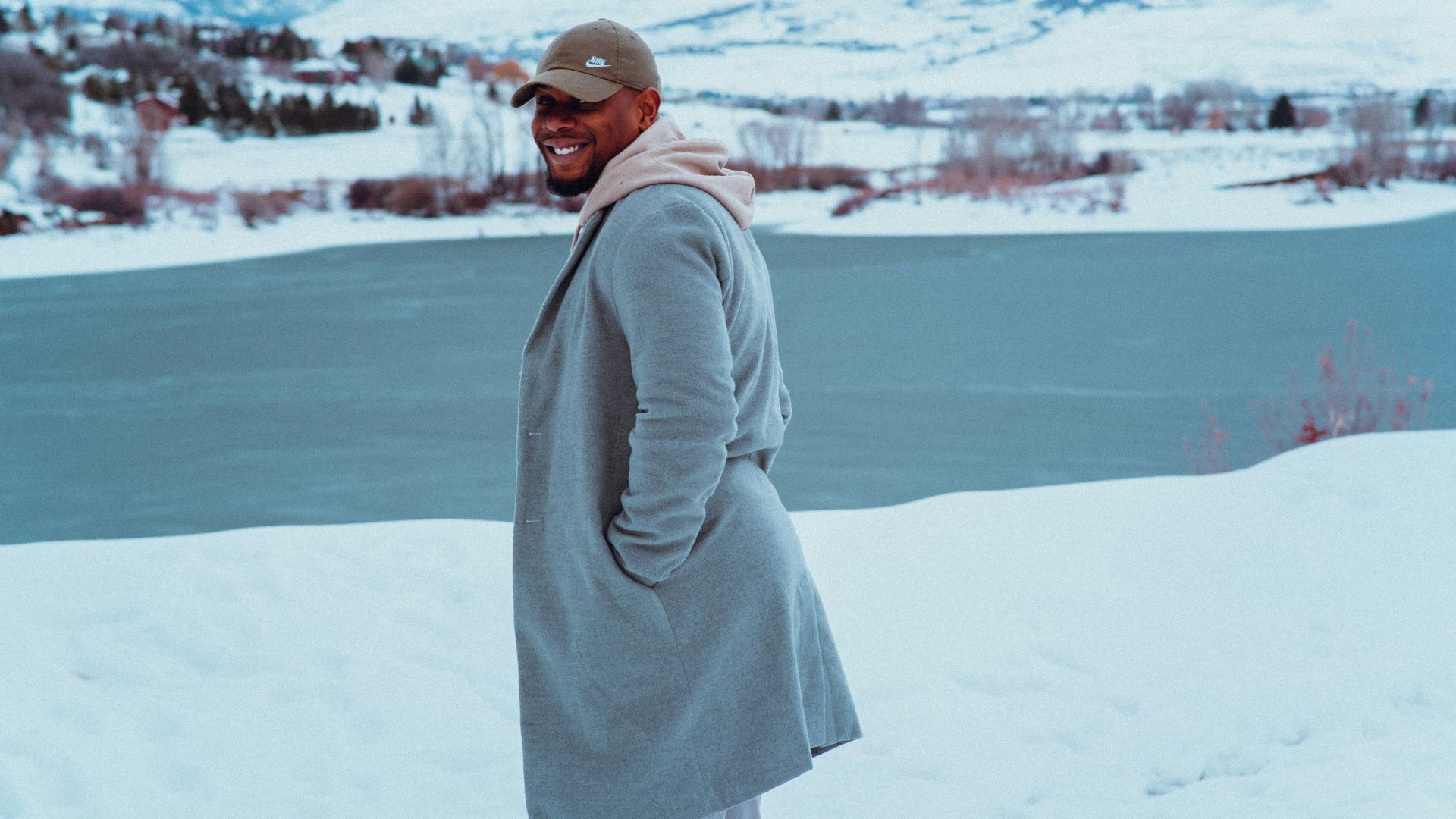 a man standing in the snow wearing a coat and hat