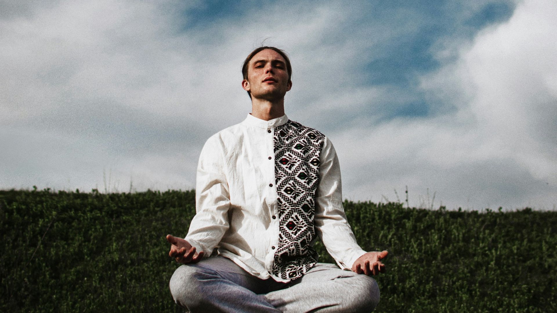 a man sitting on top of a rock in a field