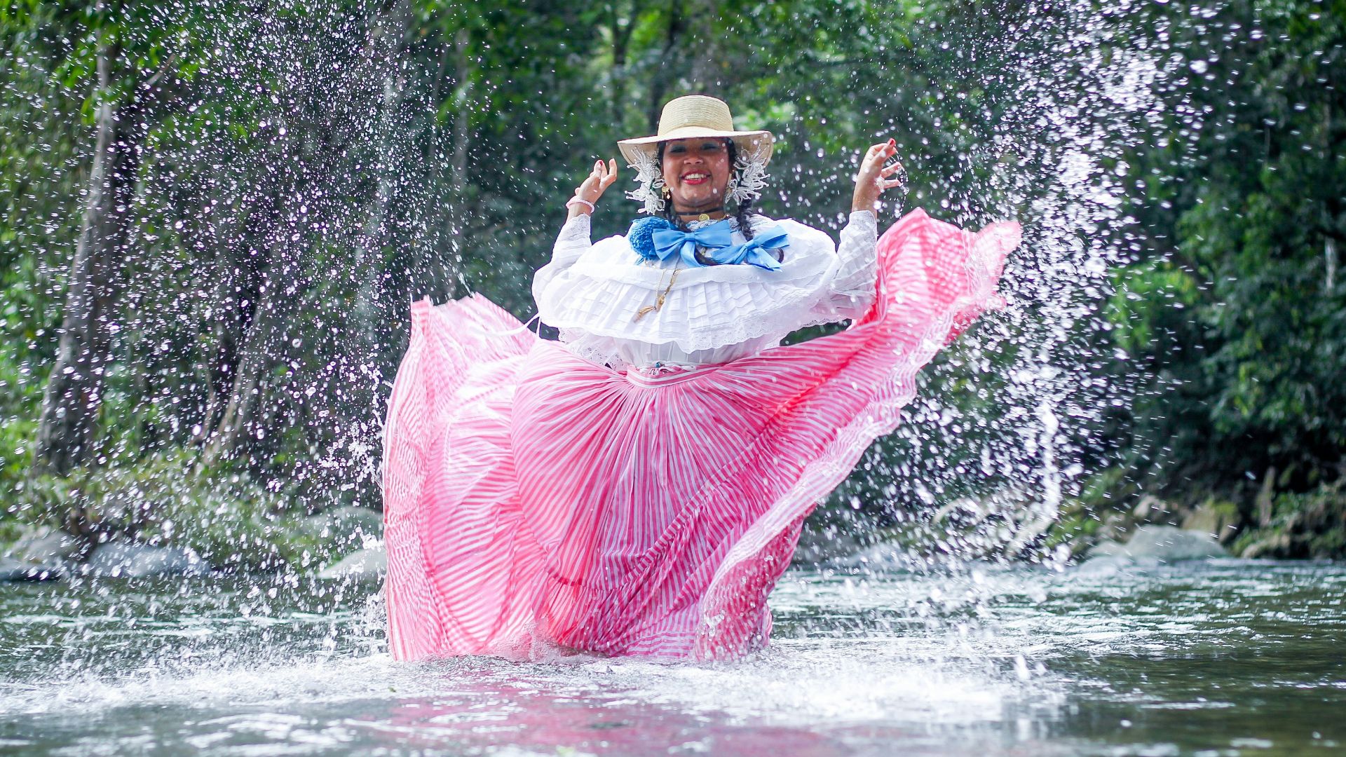 a person in a pink and white dress in a river with a pink and white fish jumping out