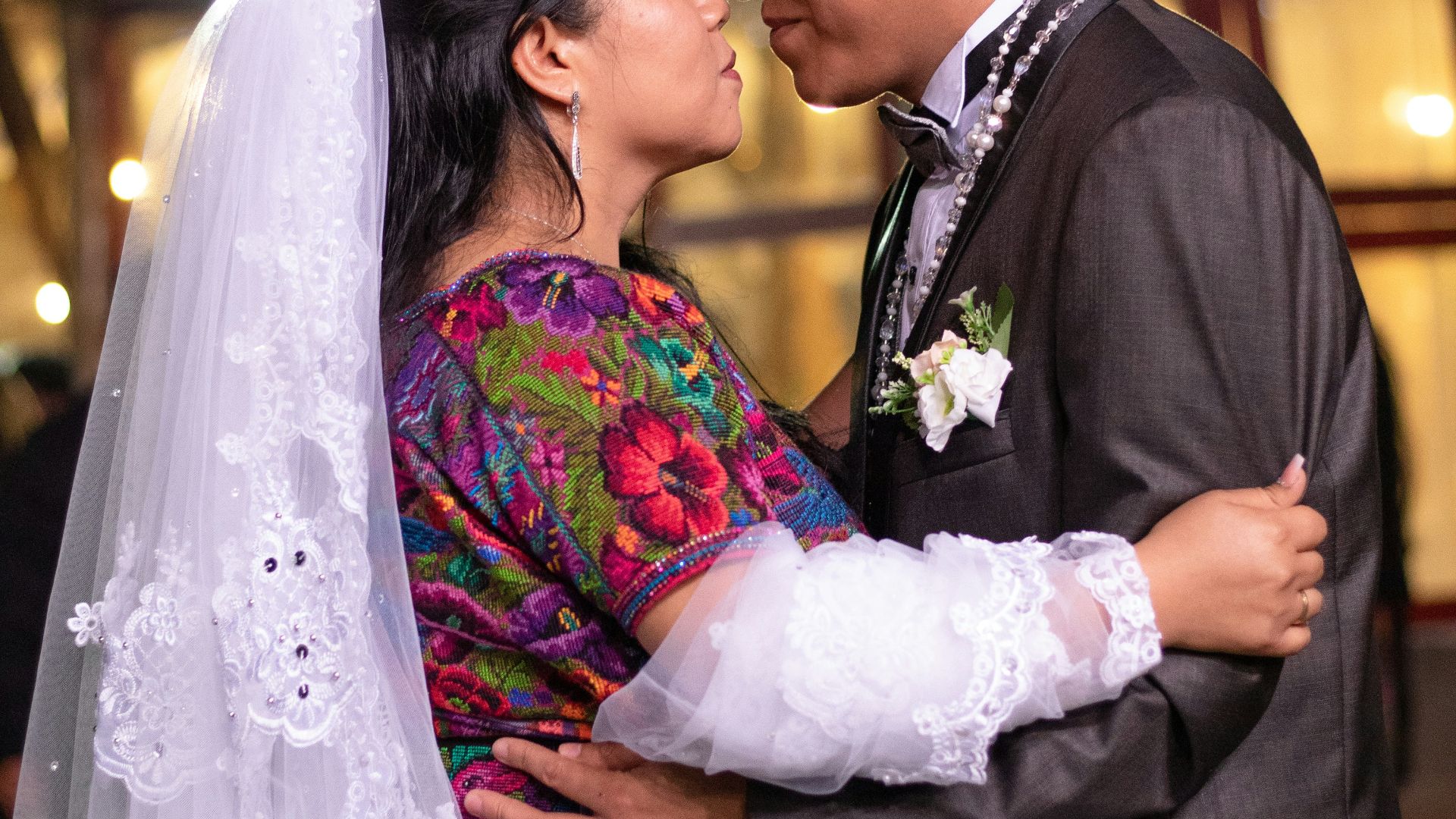 man in black suit kissing woman in white wedding dress