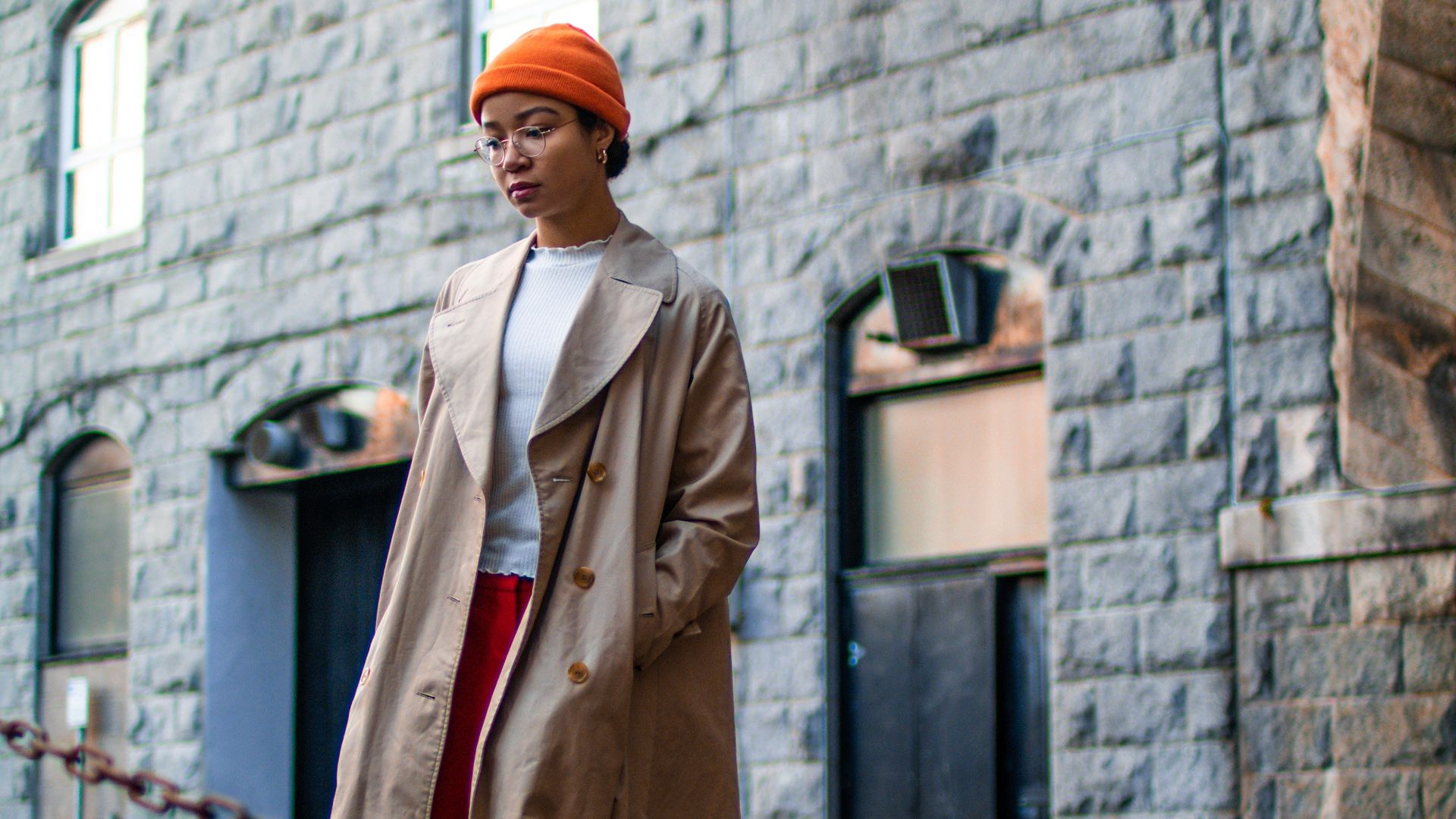 woman wearing brown coat standing besides brown steel chain
