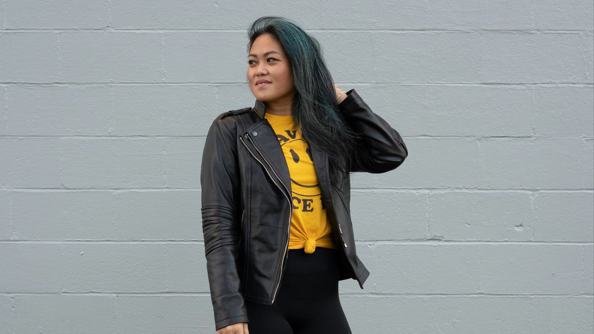 woman in black jacket and black pants standing beside white wall