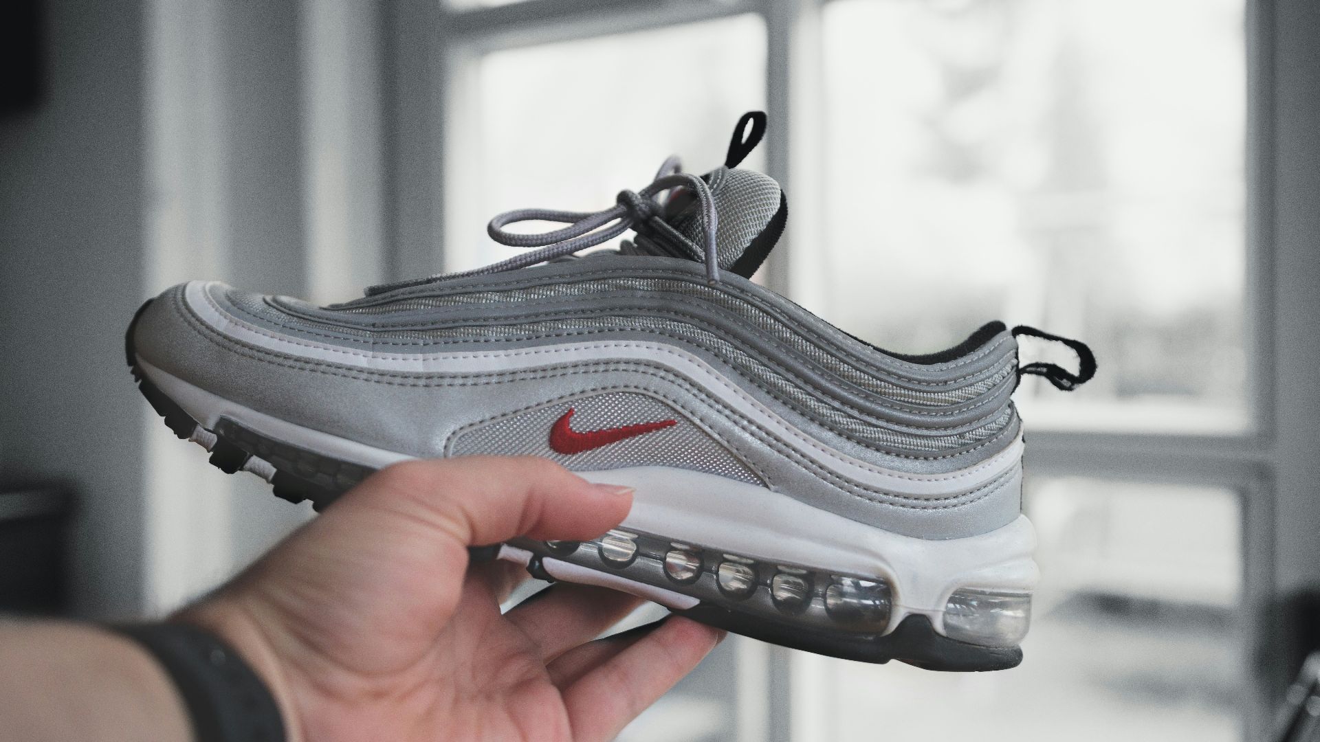 person holding gray and white nike athletic shoe