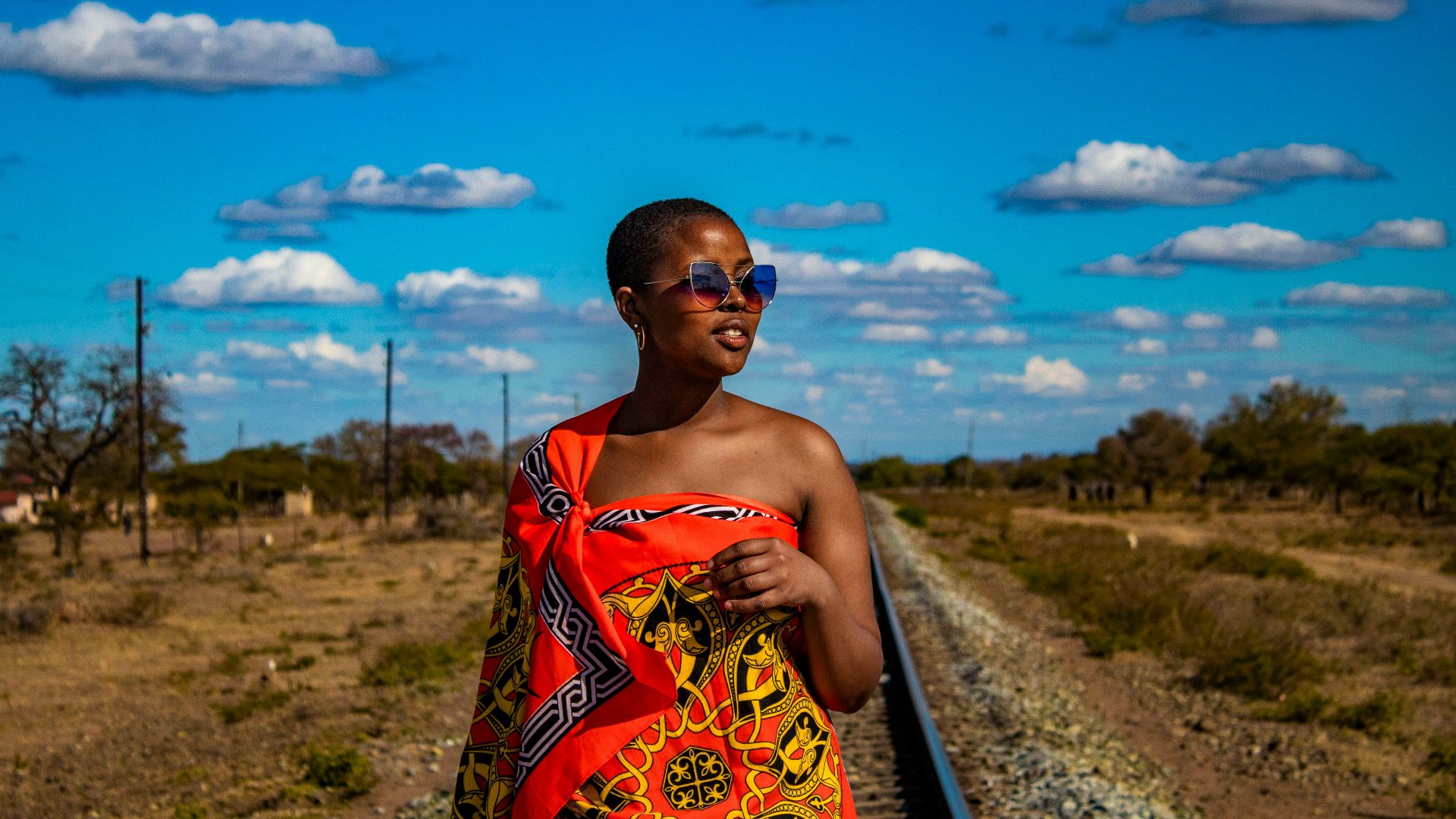 a woman in a colorful towel standing on a train track