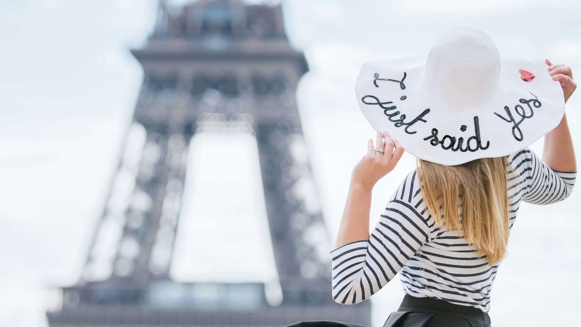 a woman sitting on a ledge in front of the eiffel tower