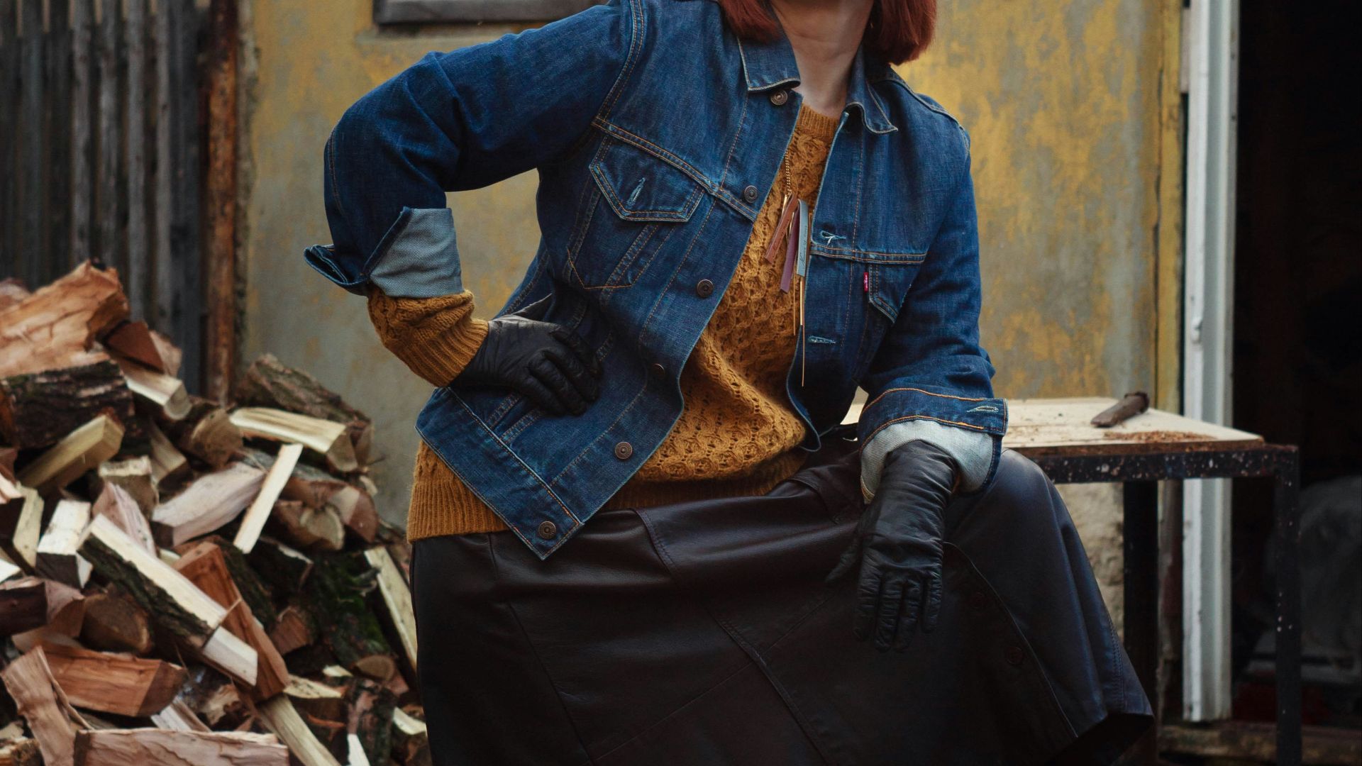 brown haired woman in blue denim jacket standing near firewoods