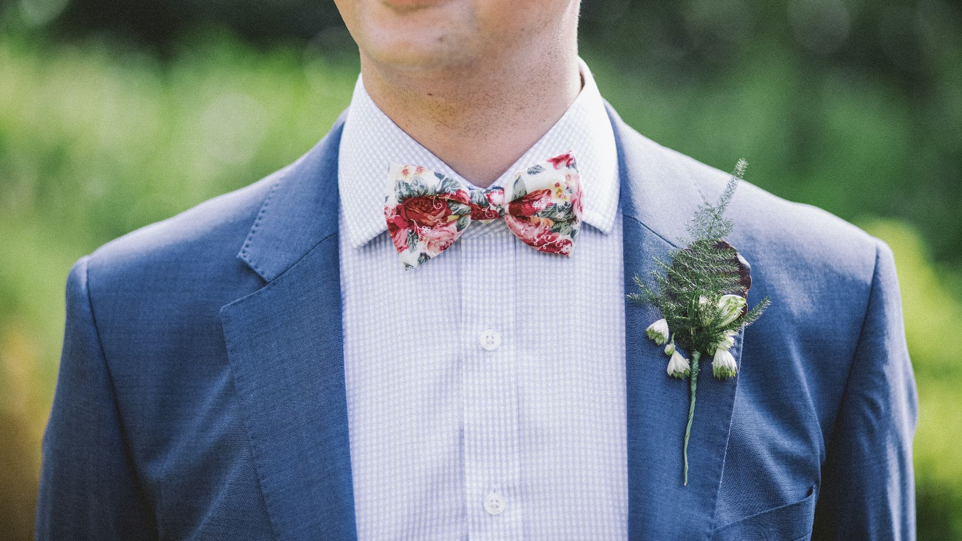 man wearing blue notched-lapel blazer with red and white bowtie at daytime