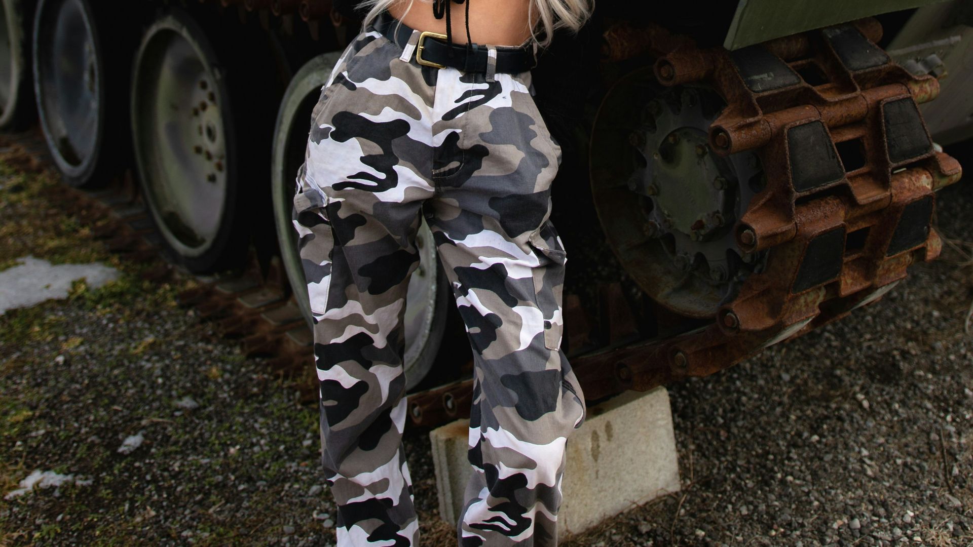 woman in green and black camouflage uniform standing beside green battle tank